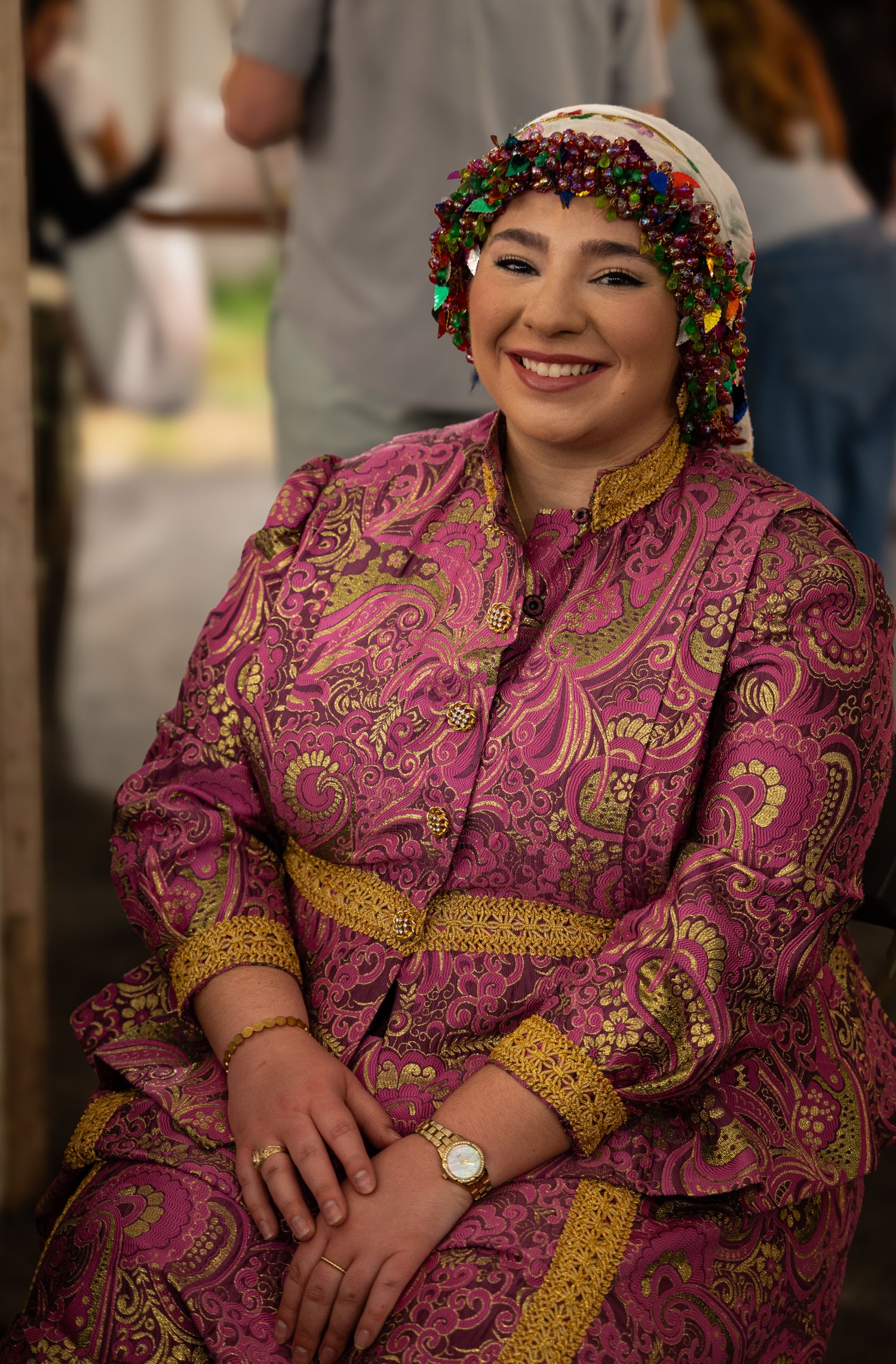 Woman in traditional Greek costume with embroidered dress and decorative headscarf smiling at a cultural festival.