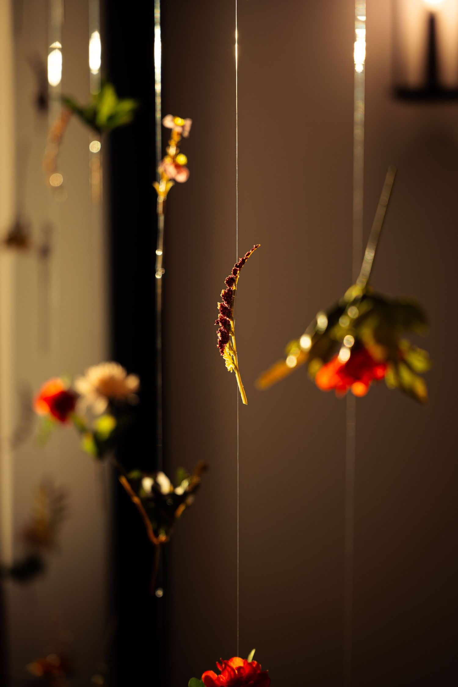 Elegant wedding decor with flowers suspended from thin strings in warm ambient lighting.