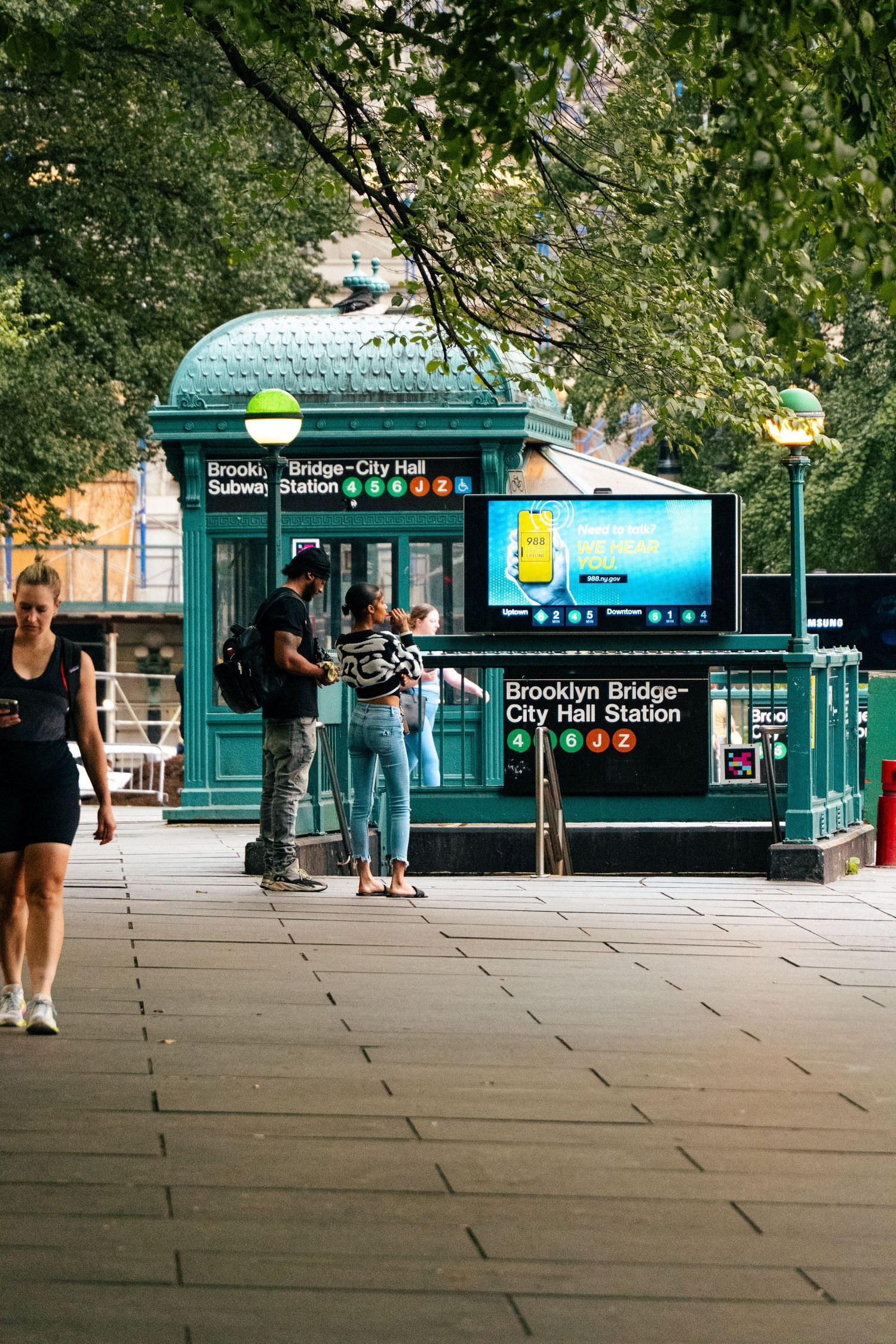 A street scene with a green and white trolley car and people standing on the platform.