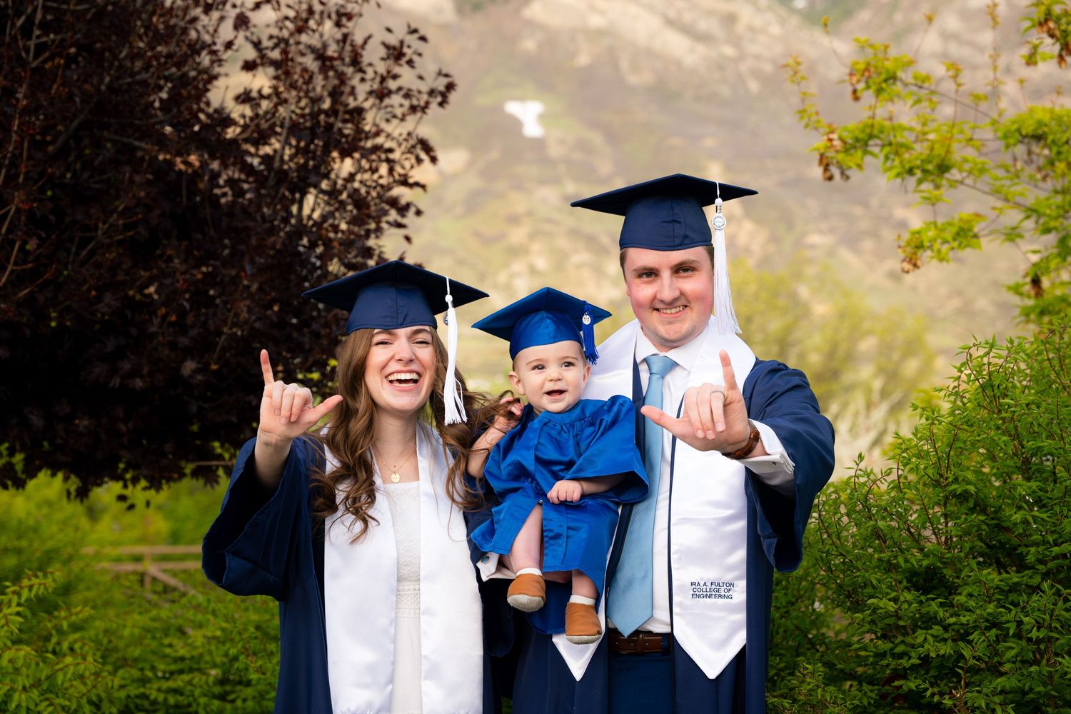 A family of four, including two adults and two children, pose for a graduation photo.