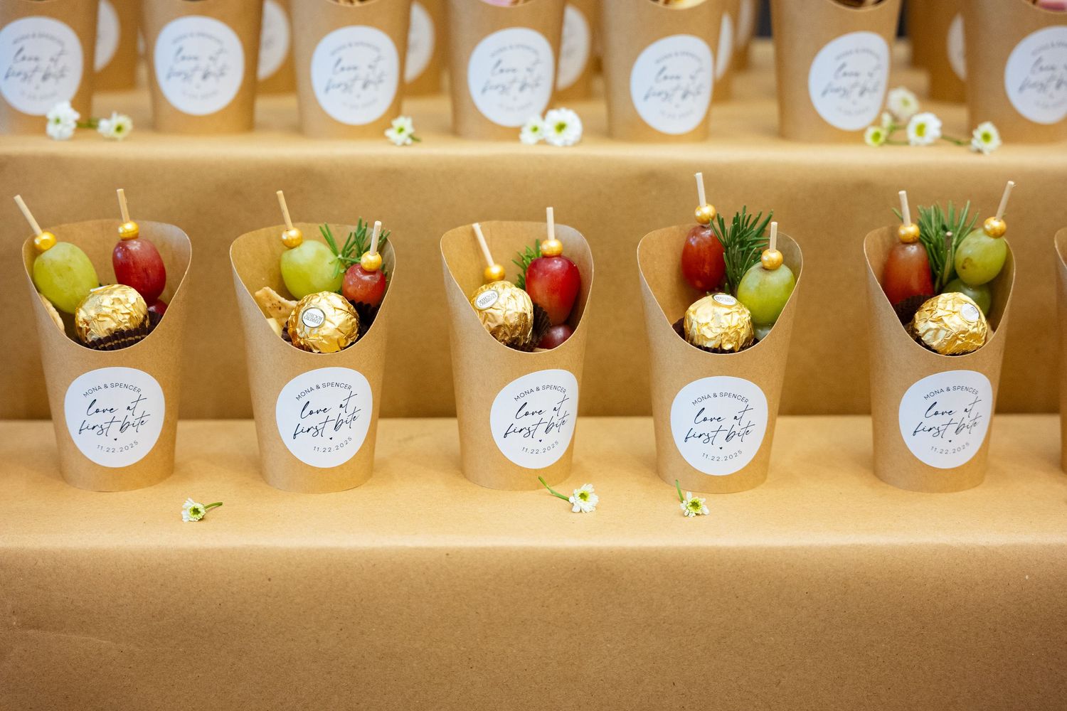 Five elegant paper cones filled with fresh fruit skewers and Ferrero Rocher chocolates displayed on a golden table.