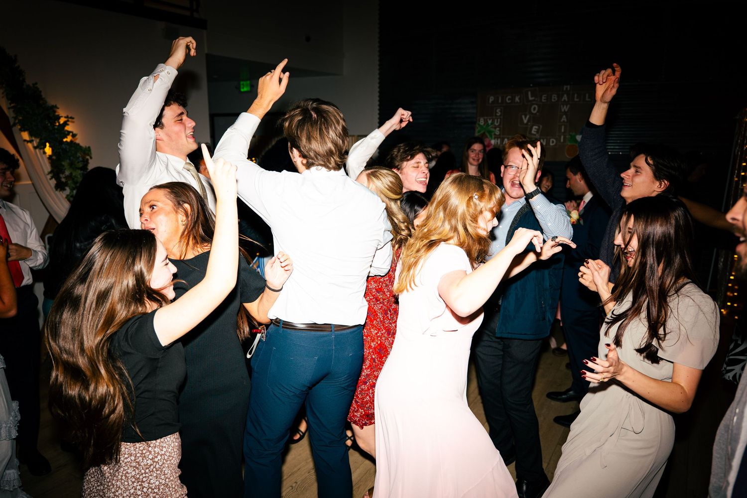 Energetic wedding reception dance floor filled with guests celebrating and dancing together.