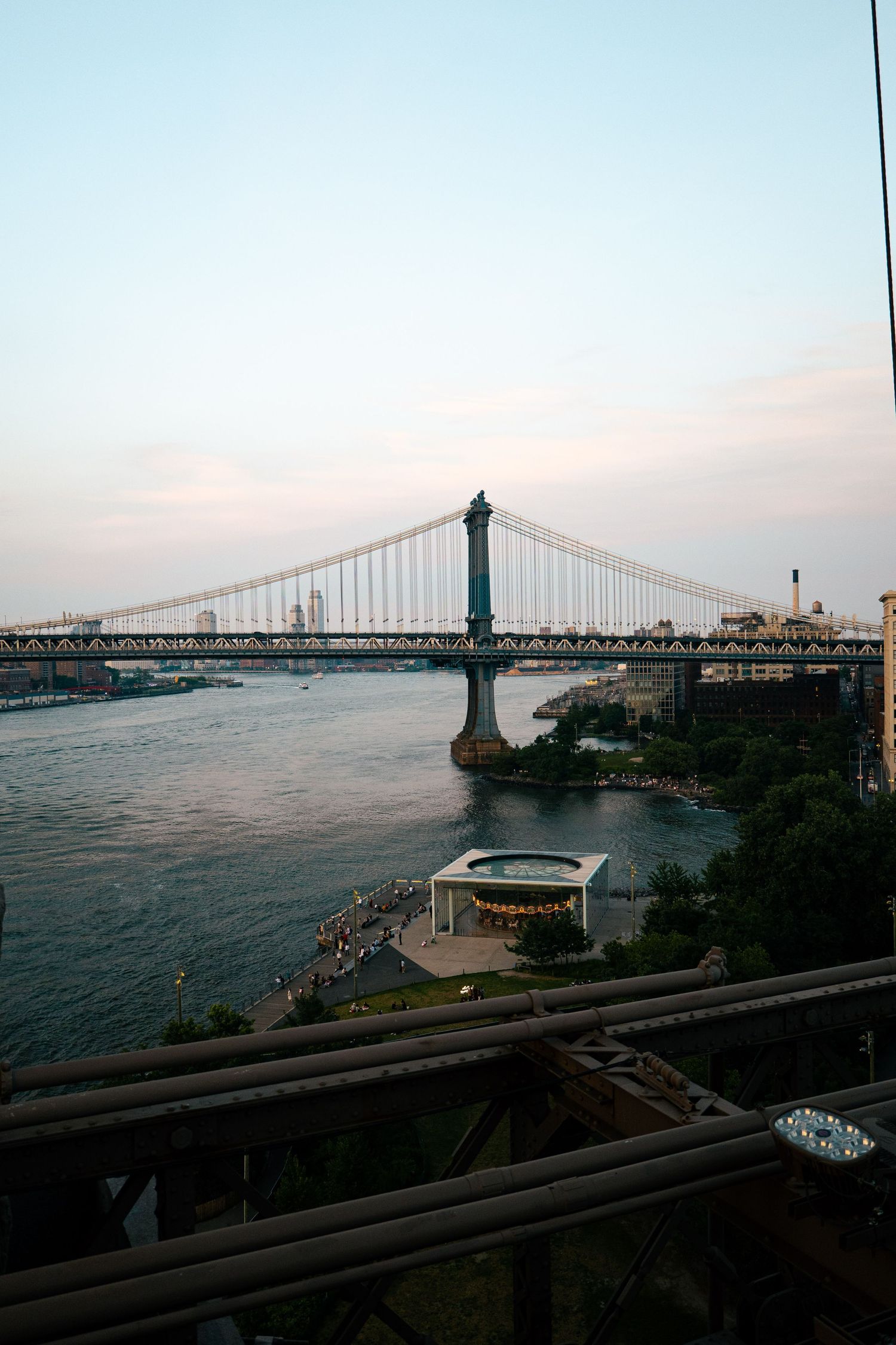 Panoramic view of the Manhattan skyline and the Brooklyn Bridge, with a small boat in the foreground.