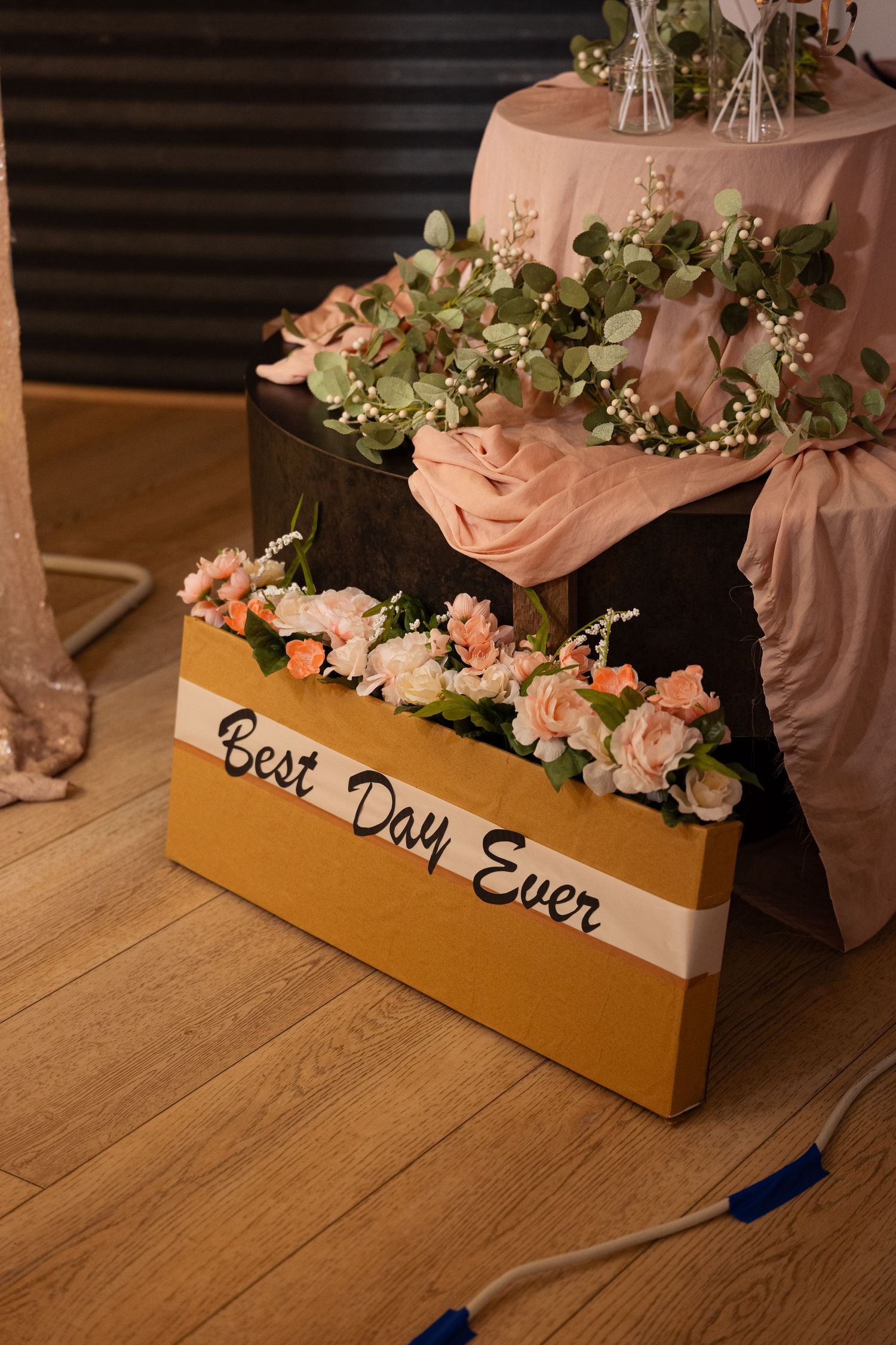 Gold floral box decorated with pink roses and the text Best Day Ever at a wedding reception.