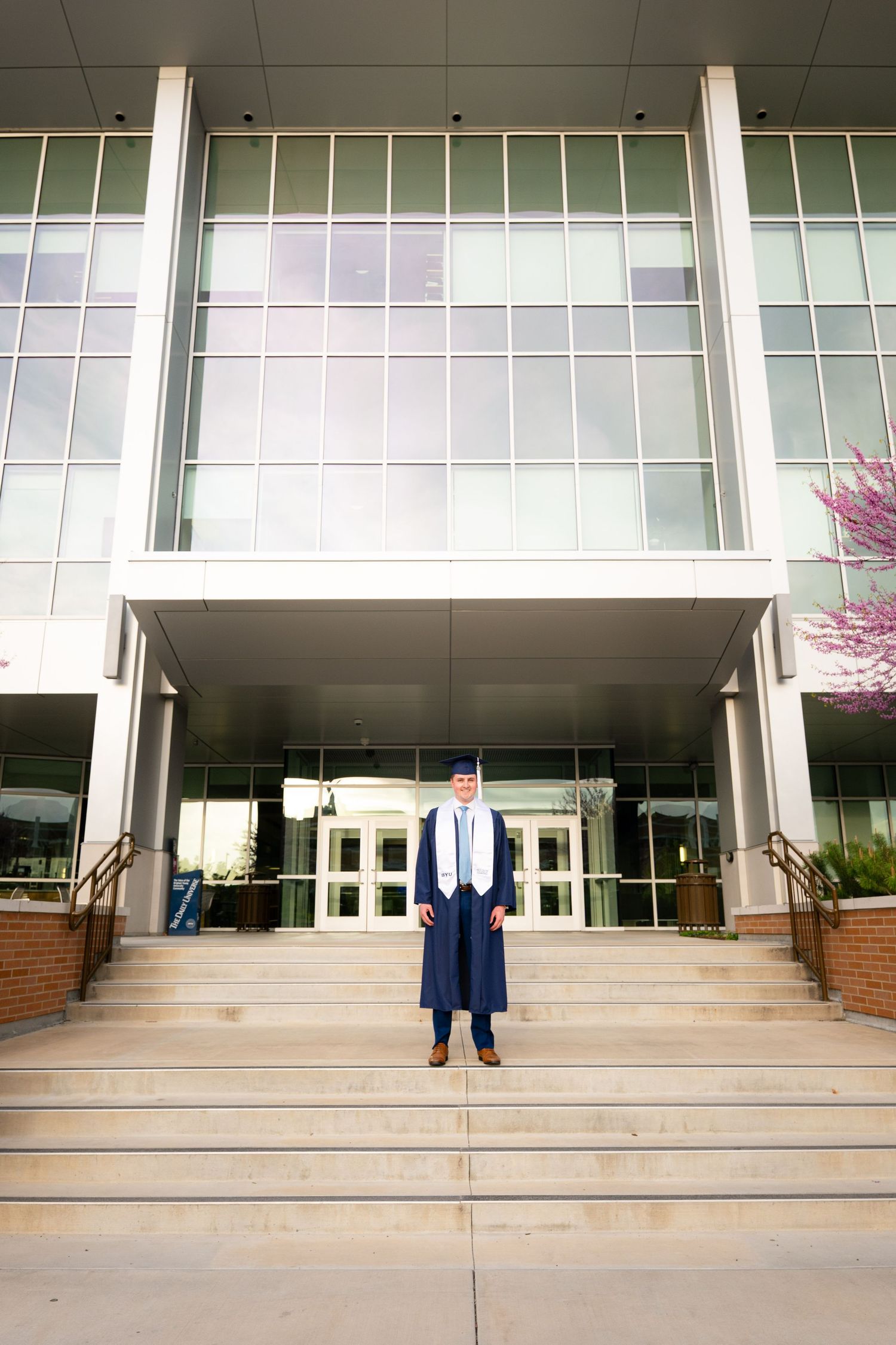 A man in a suit stands on the steps of a university building.
