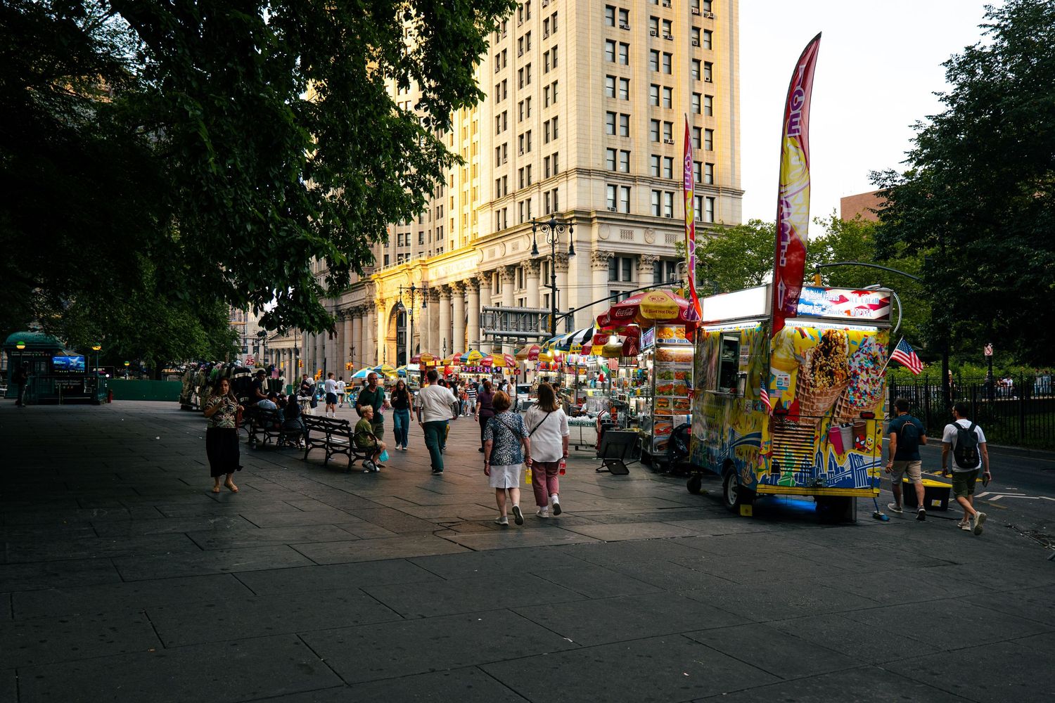 A crowded city street with various shops, food carts, and people walking by.