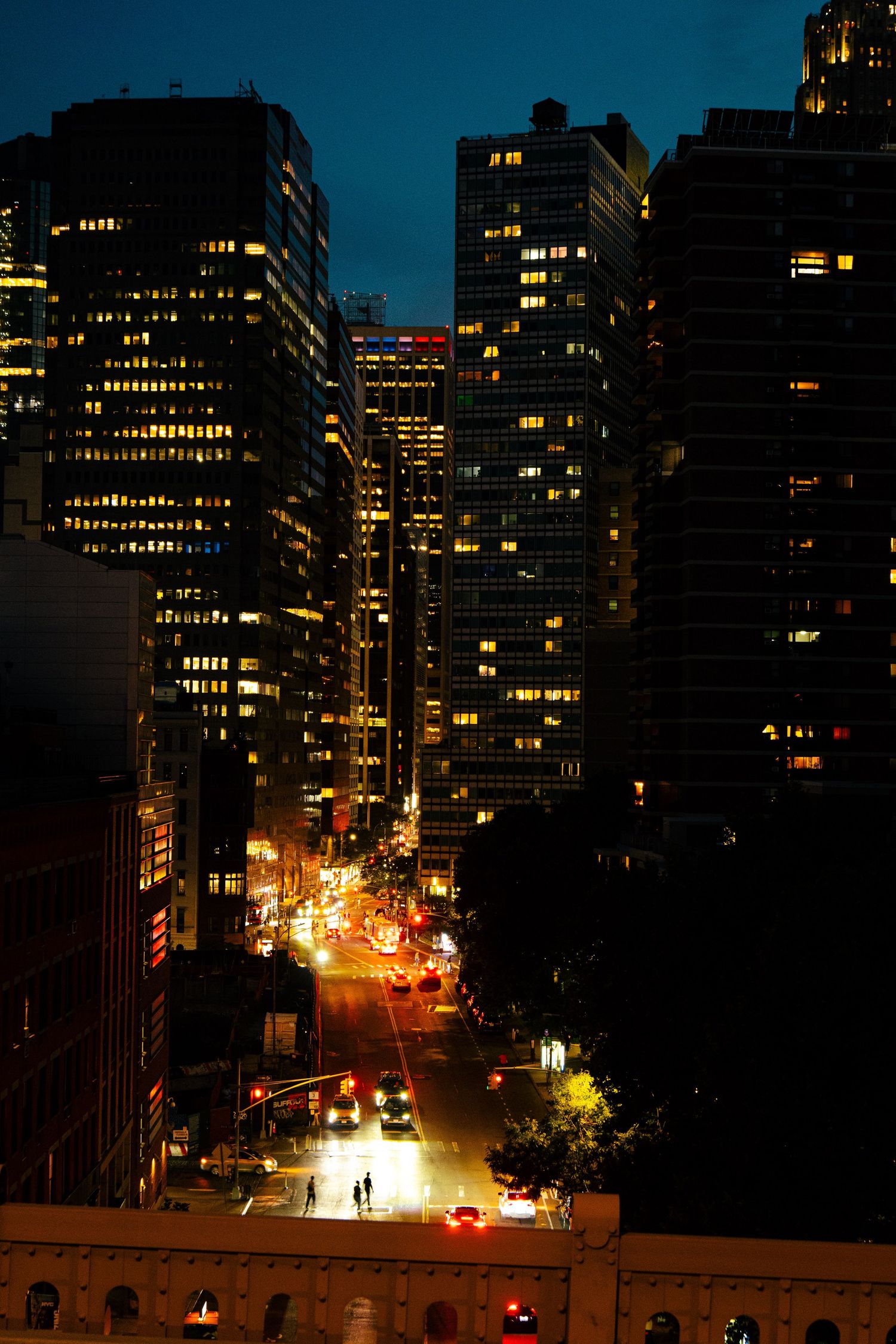Nighttime cityscape with illuminated high-rise buildings and streets in the foreground.