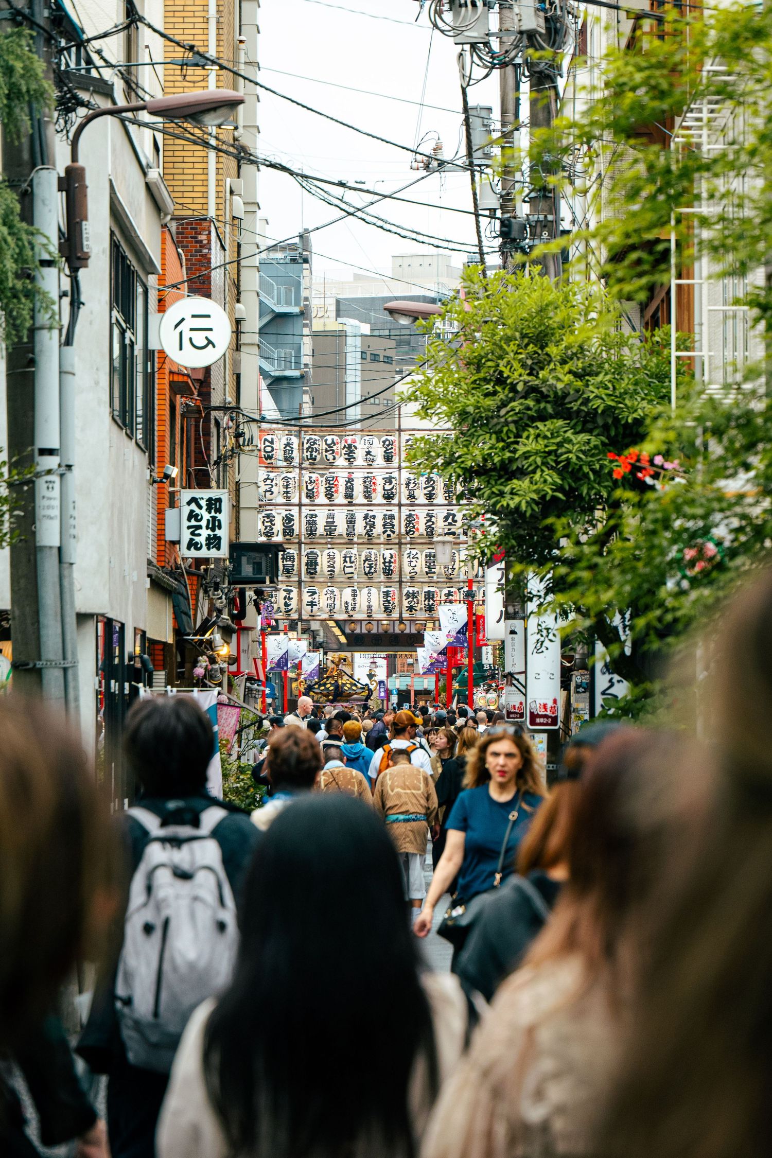 A bustling street in Japan filled with people, shops, and traditional lanterns, capturing the energy and liveliness of the local culture.