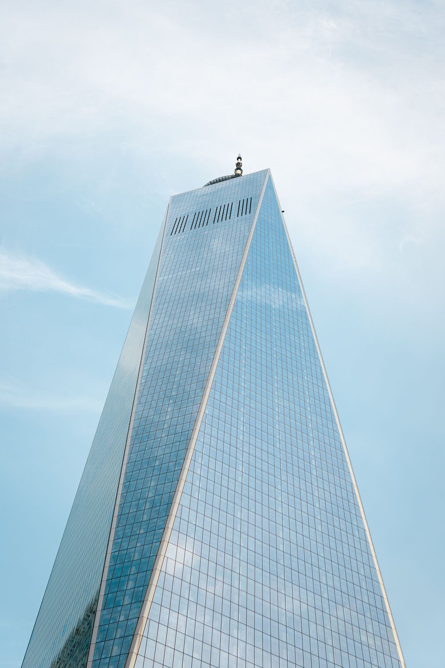 A tall, modern skyscraper reaching up towards the sky, with a person standing on the roof of the building.