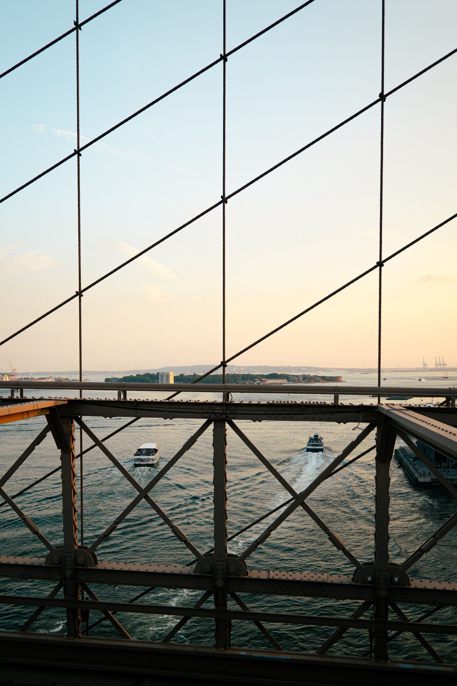 A view through the glass panels of a building, overlooking the New York City skyline and the waters of the harbor.