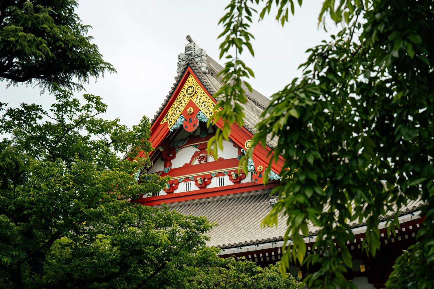 A traditional Japanese temple building with an ornate, colorful roof and surrounded by lush greenery.