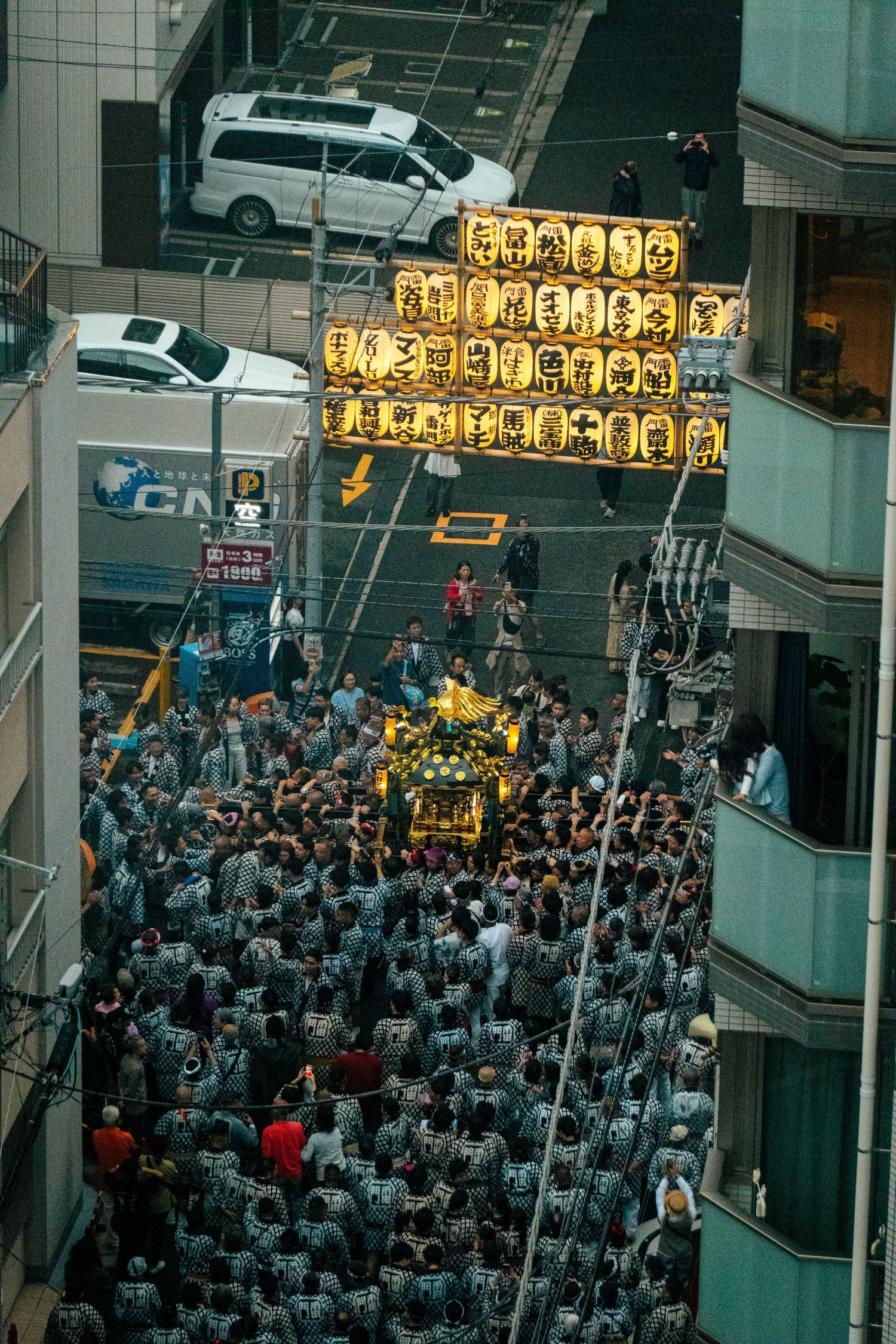 A crowded street scene with a large number of people gathered, some carrying yellow flags or banners.