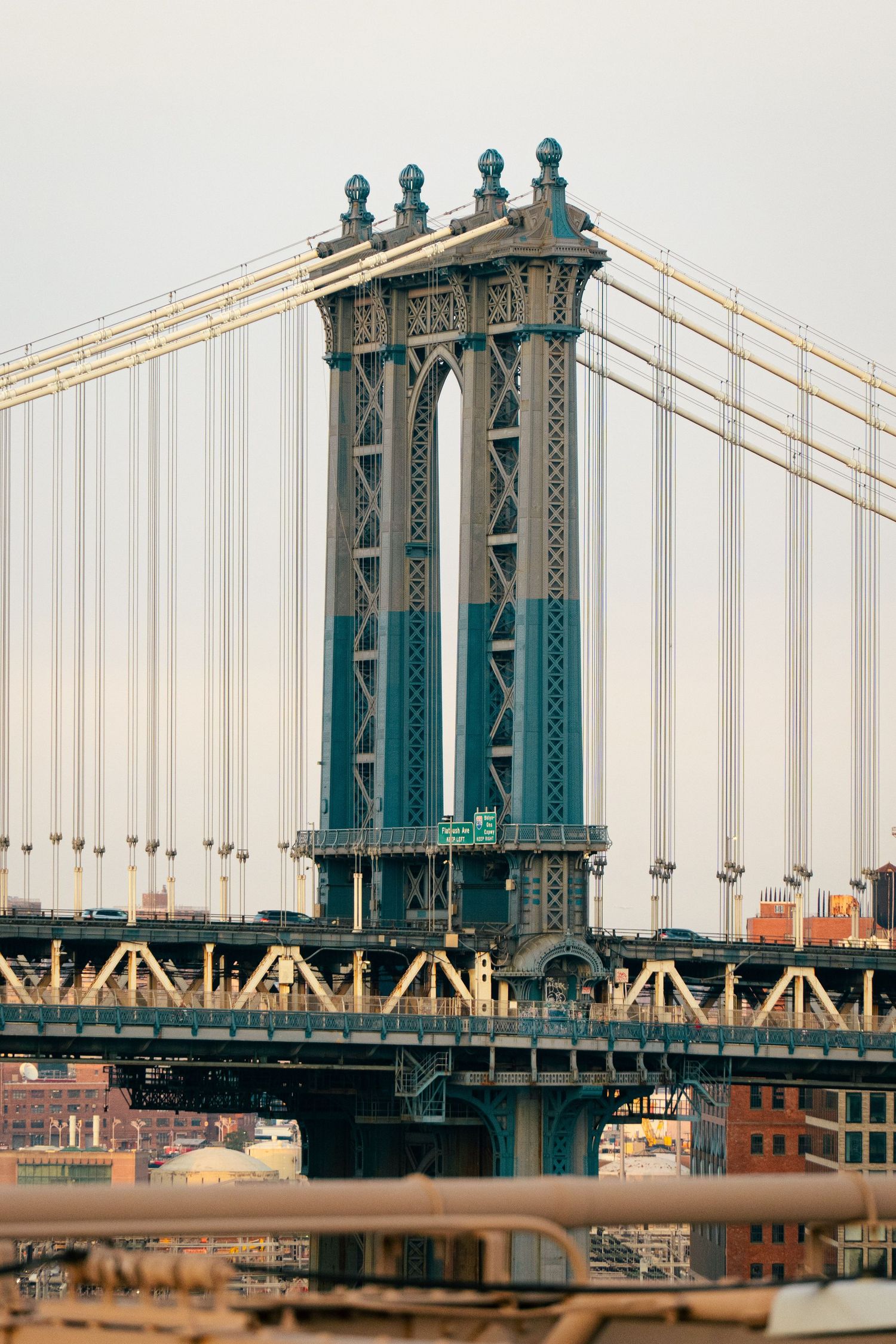 The image shows a grand suspension bridge with intricate architectural details and towers, reflecting in the water below.