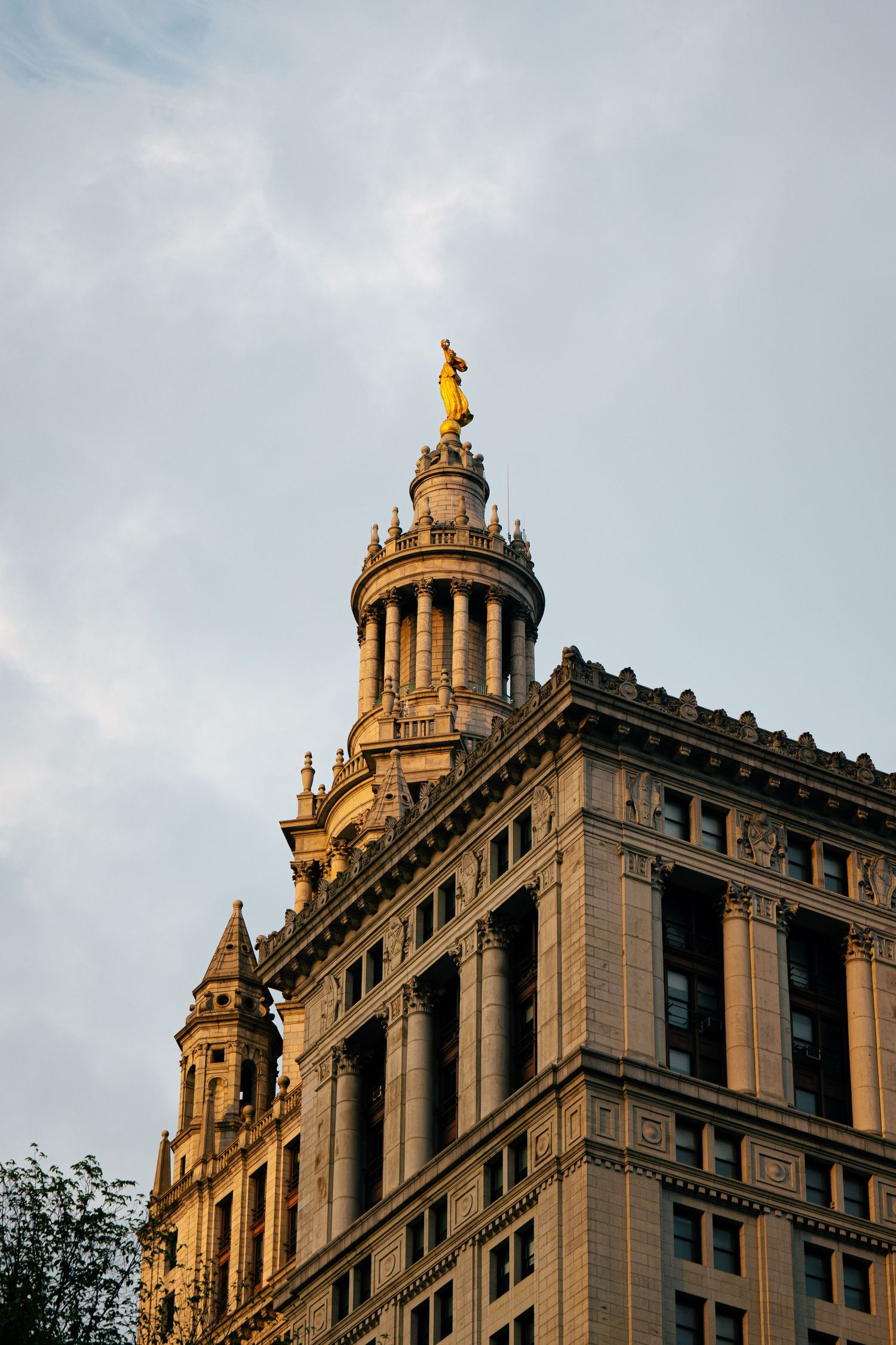 A tall, ornate building with multiple towers and decorative elements against a cloudy sky.