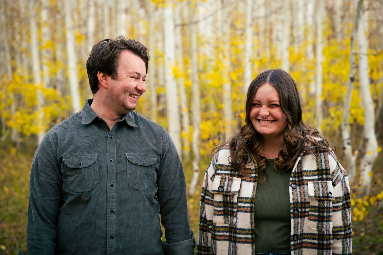 The image shows a couple walking together in a forest with fall foliage.