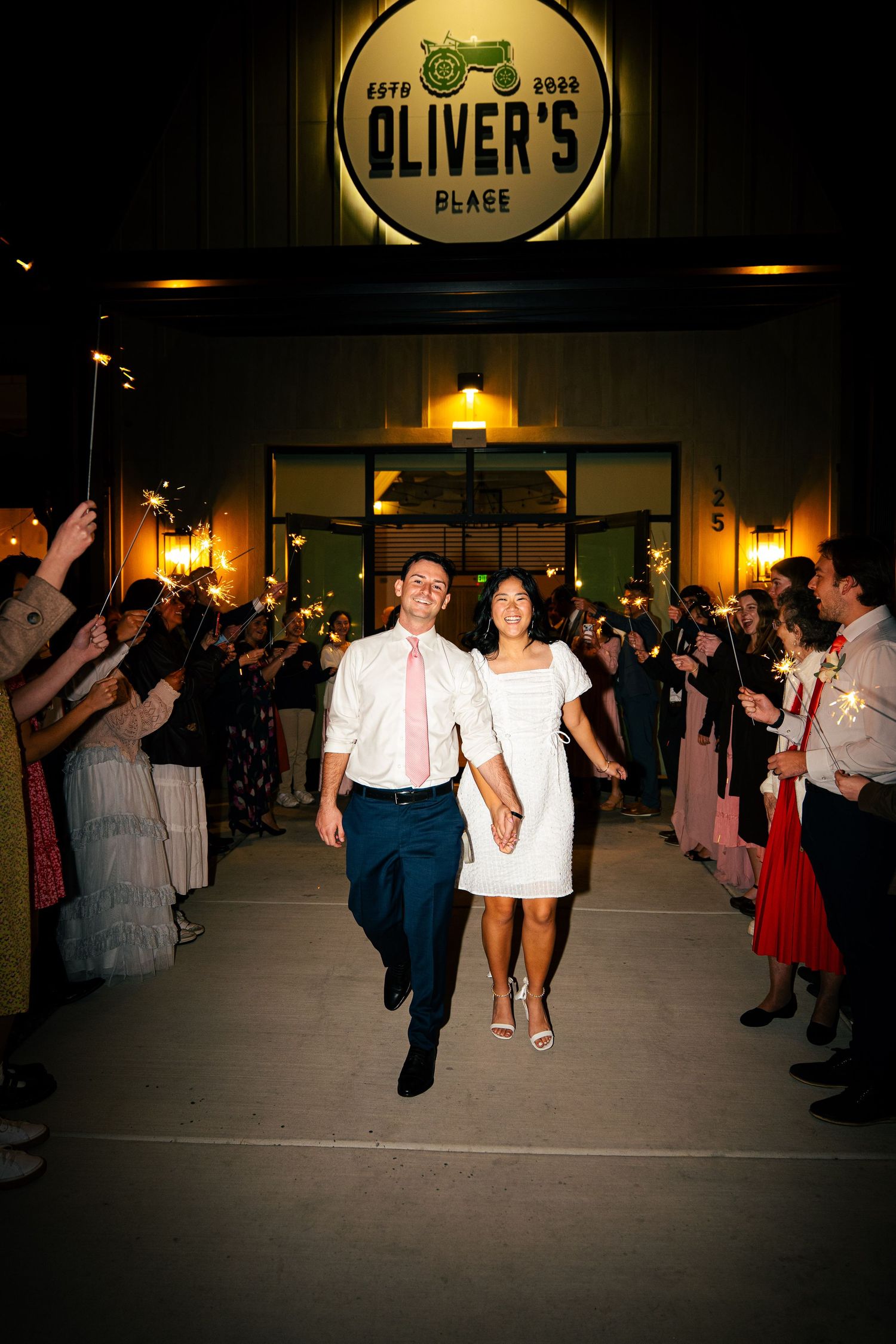 Couple exits wedding reception at Oliver's Place venue through sparkler send-off at night.