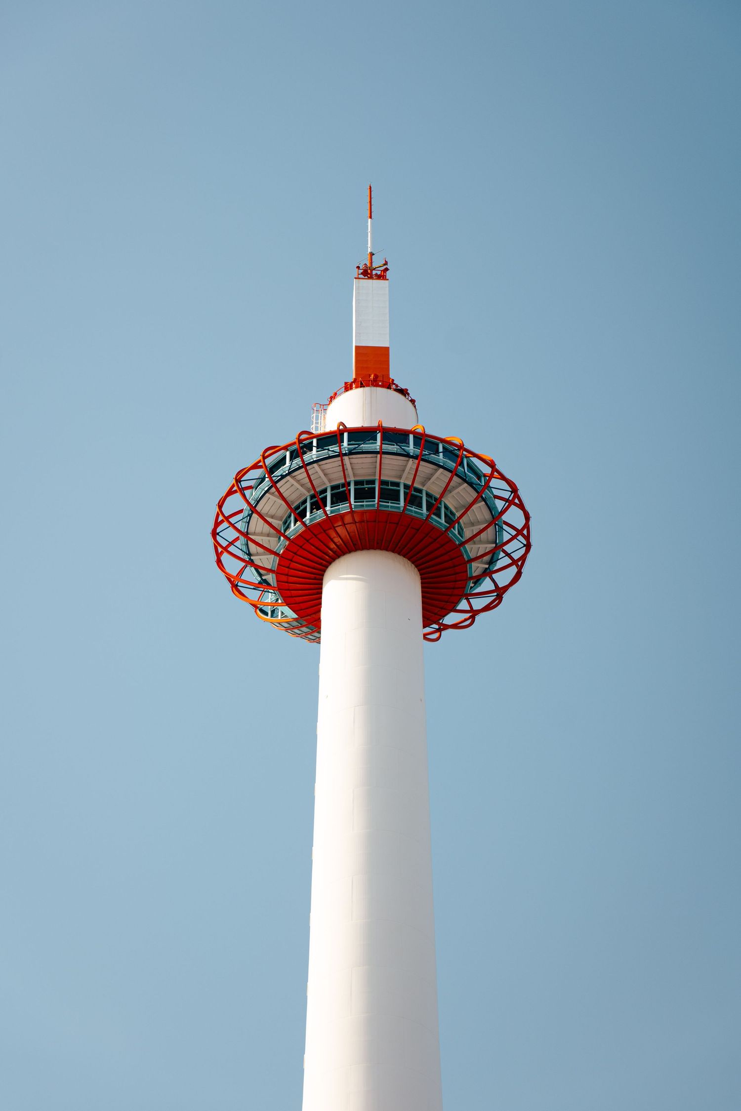 A tall, red and white communication tower stands against a clear blue sky.