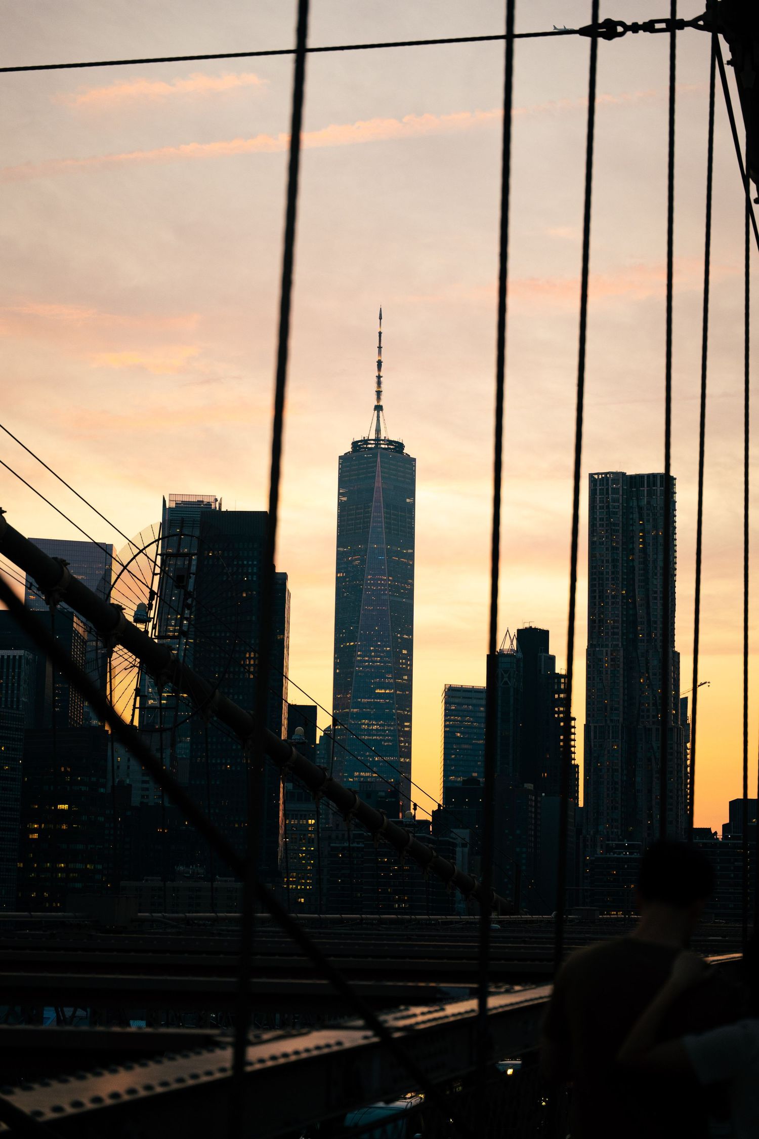 Silhouetted cityscape of New York City, with the One World Trade Center tower visible at sunset.