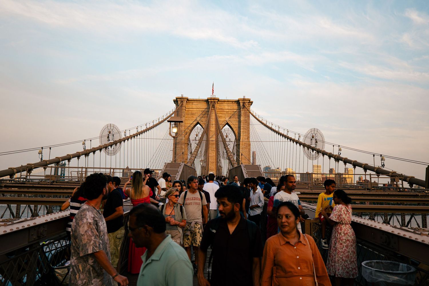 A crowded view of the iconic Brooklyn Bridge in New York City, with pedestrians crossing the suspension bridge.