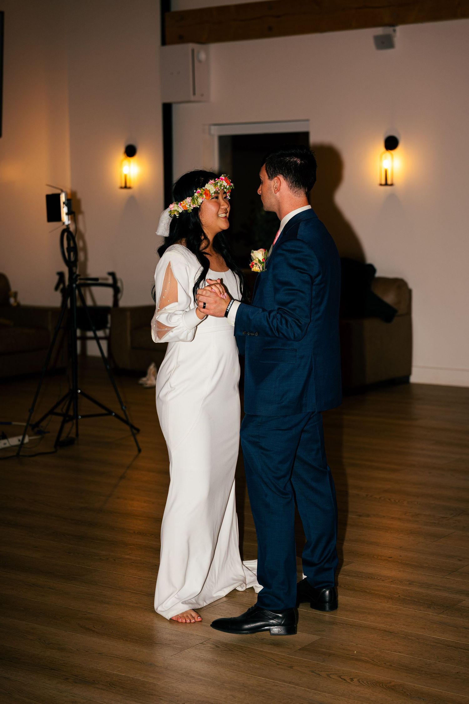 Bride and groom share first dance in dimly lit wedding reception venue.