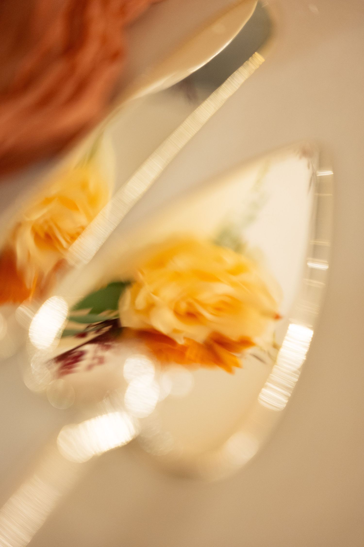 Blurred close-up of elegant floral wedding cake server with yellow rose detail and silver knife.