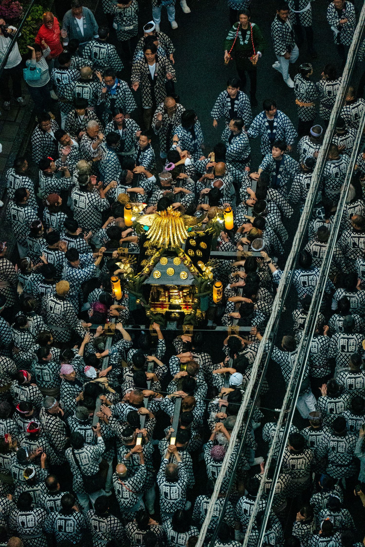 An aerial view of a crowded city street filled with a large gathering of people, with buildings and structures surrounding the area.