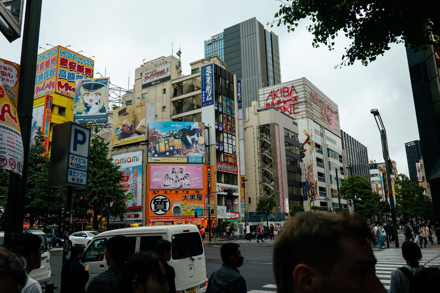 A busy city street in Japan with tall buildings and advertisements.