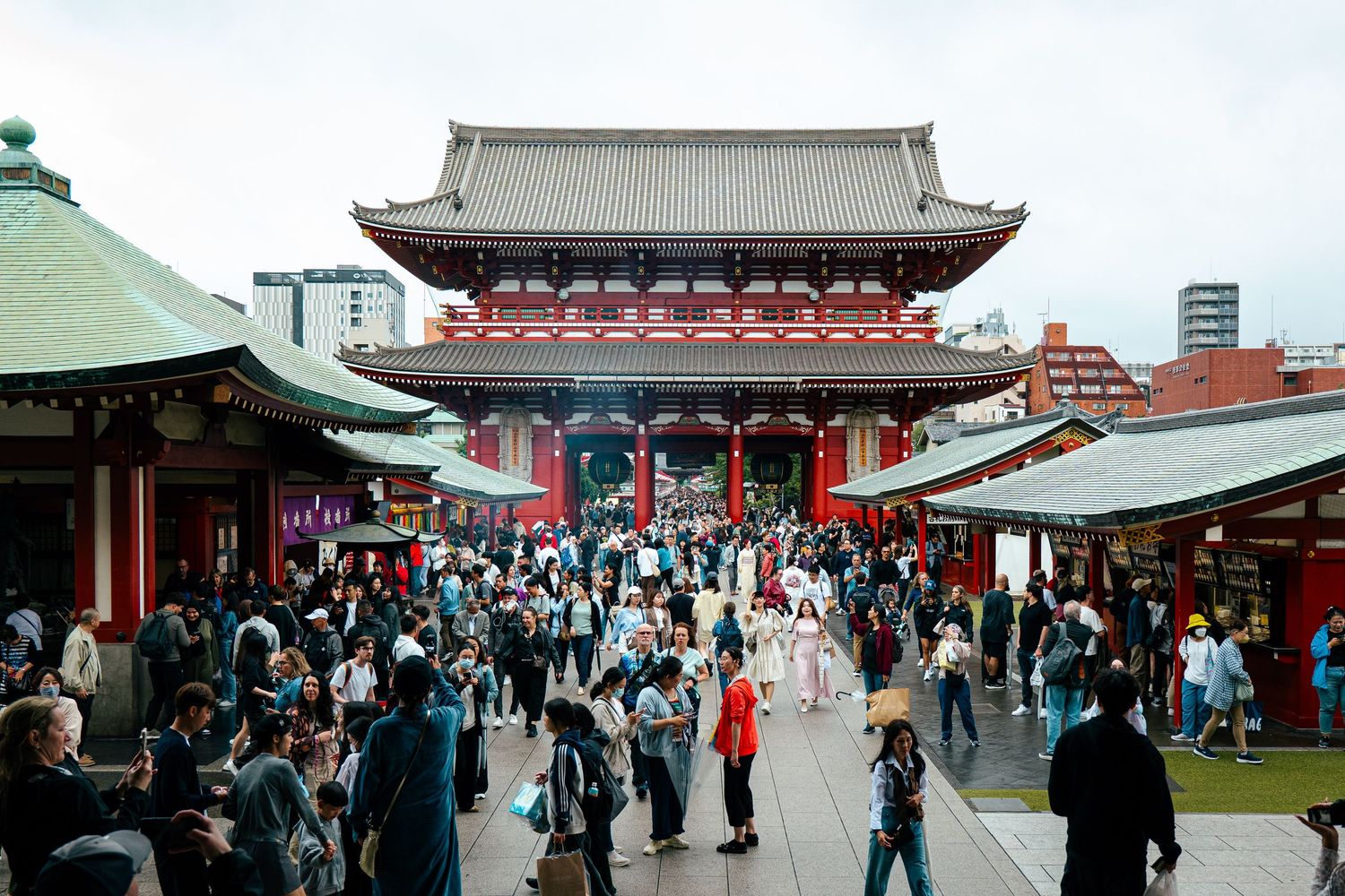 A crowded street in Japan with a large red gate and traditional Japanese architecture.