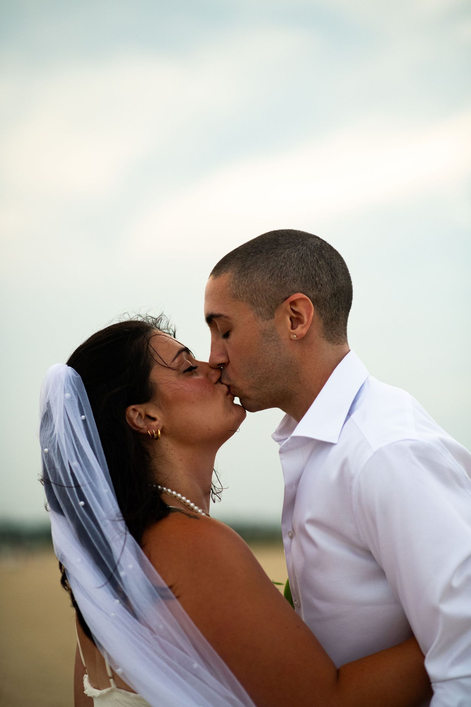 Bride and groom kissing on the beach during wedding portrait session.