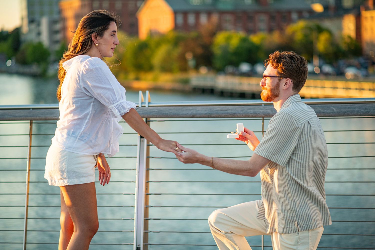 Proposal on waterfront bridge in a major city at golden hour.