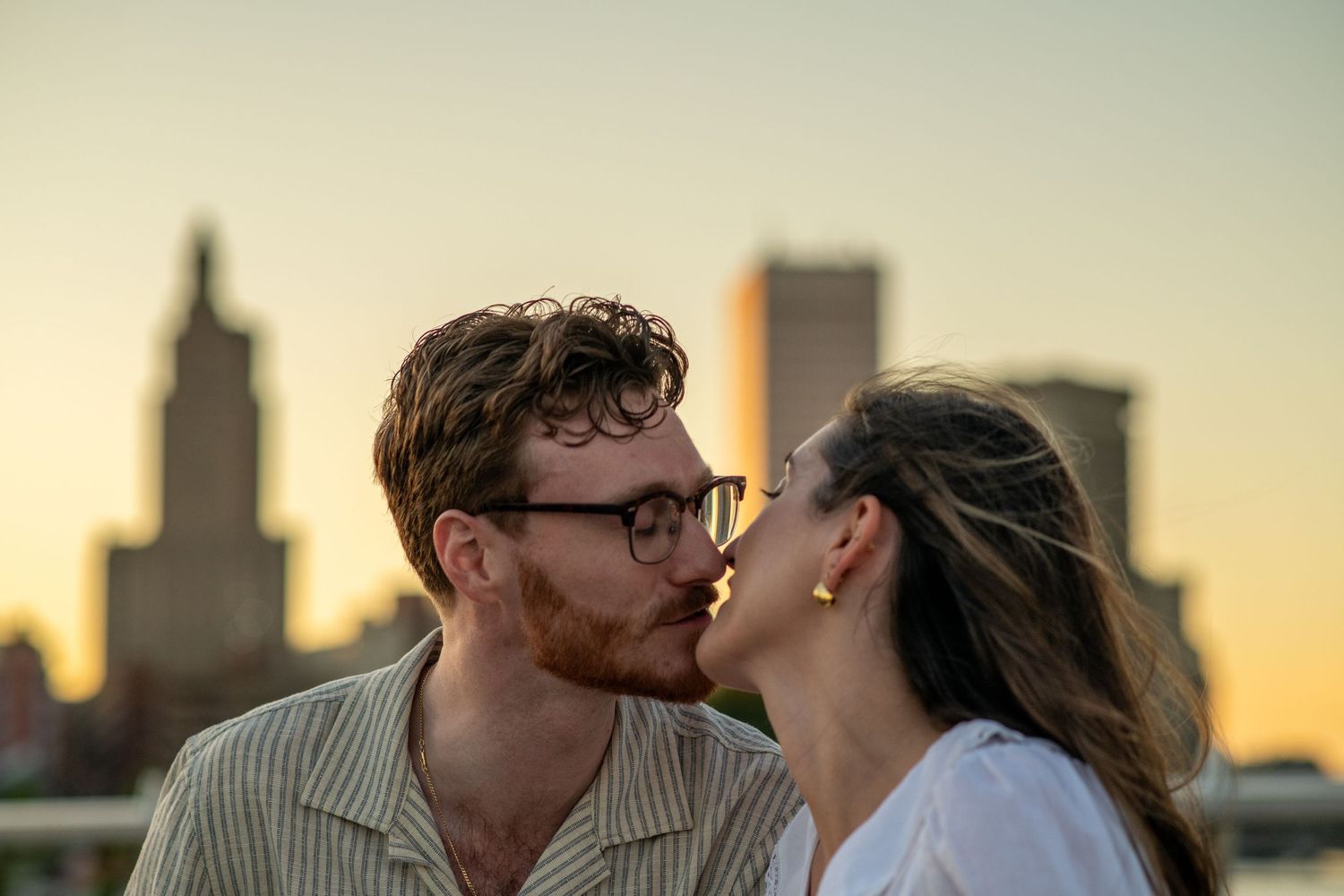 Couple portrait with city skyline at sunset during proposal session.