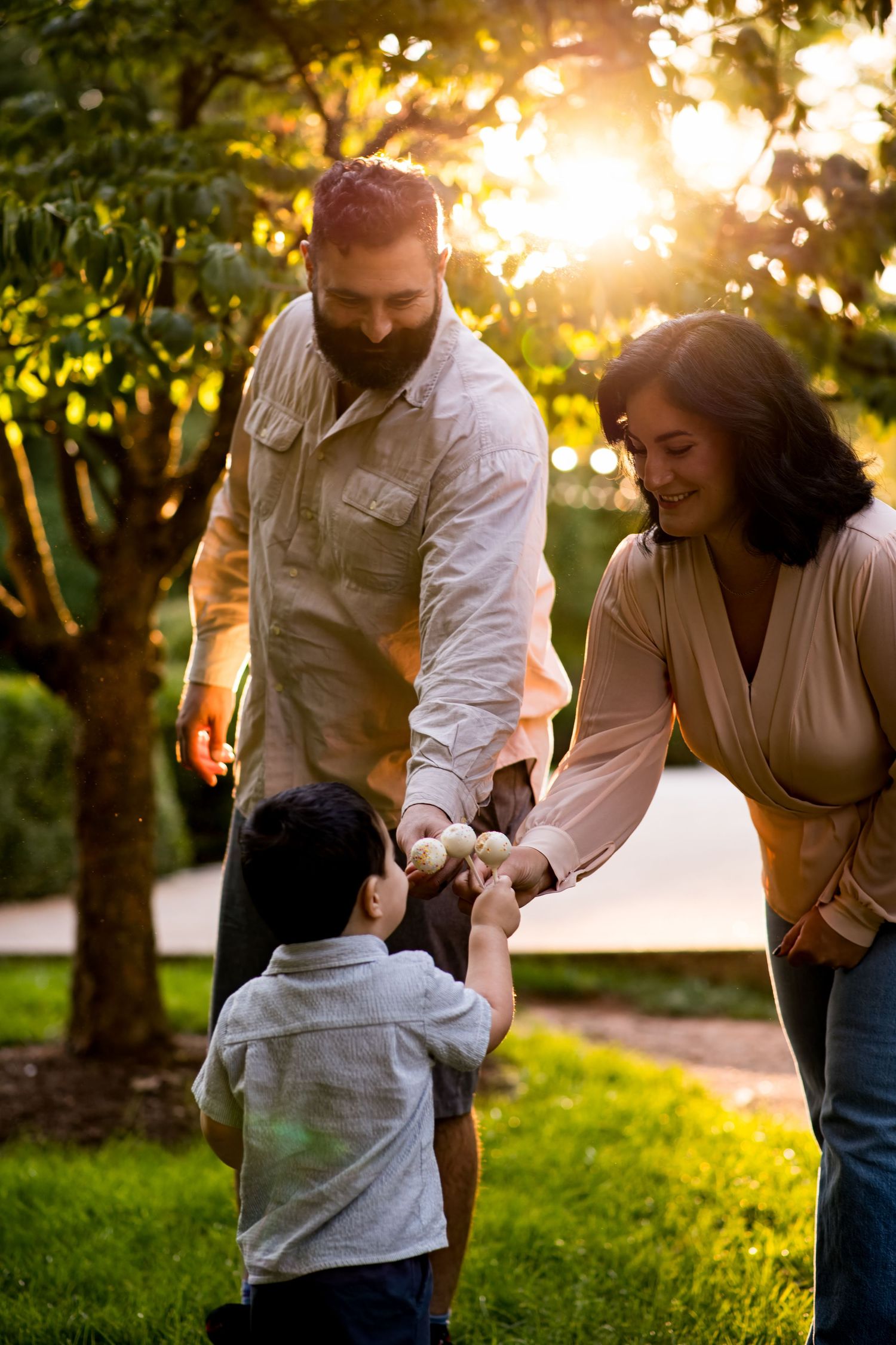 Parents and young child during an outdoor family session at sunset.