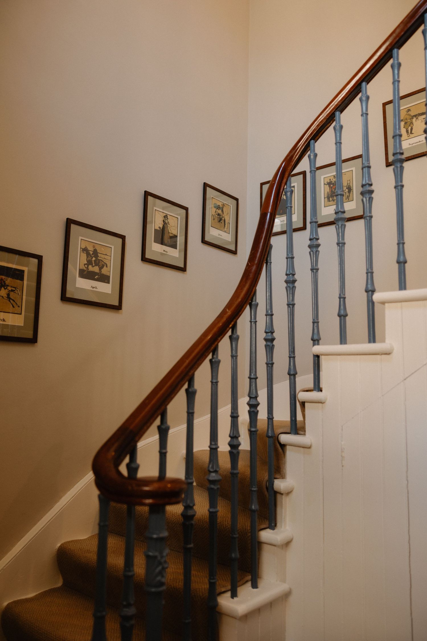 A series of photos showing a curved wooden staircase with light blue painted balusters and framed artwork on the wall.