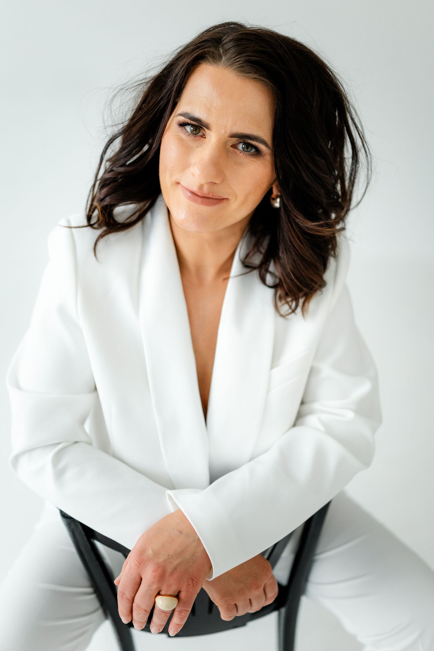 Professional headshots and poses in crisp white blazer against light background.