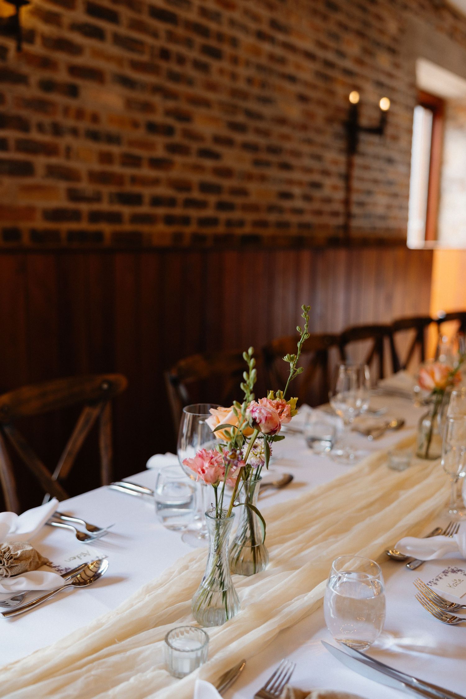 Rustic wedding reception tables set with delicate floral centerpieces in mason jars.