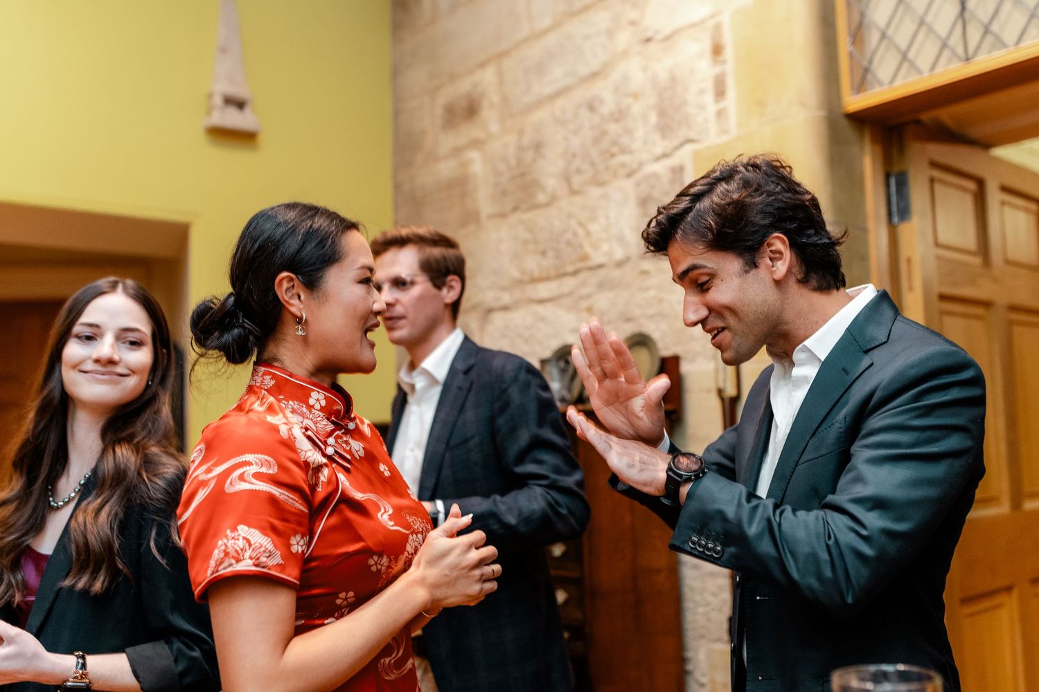 Guests laugh and socialize during a formal indoor celebration.