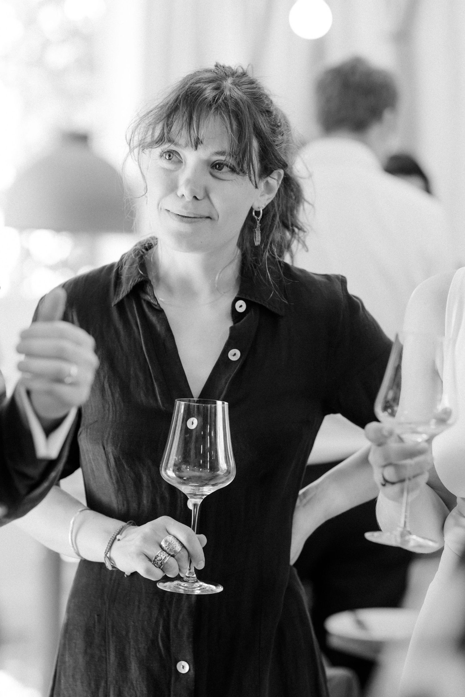 Black and white photo of someone holding a wine glass during a social event.