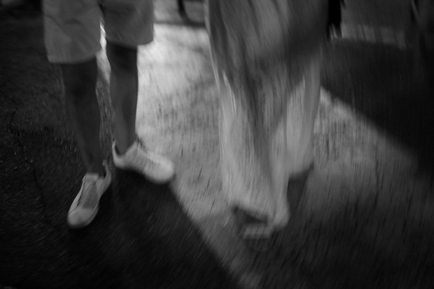 Abstract black and white motion blur of moving figures against dark background.