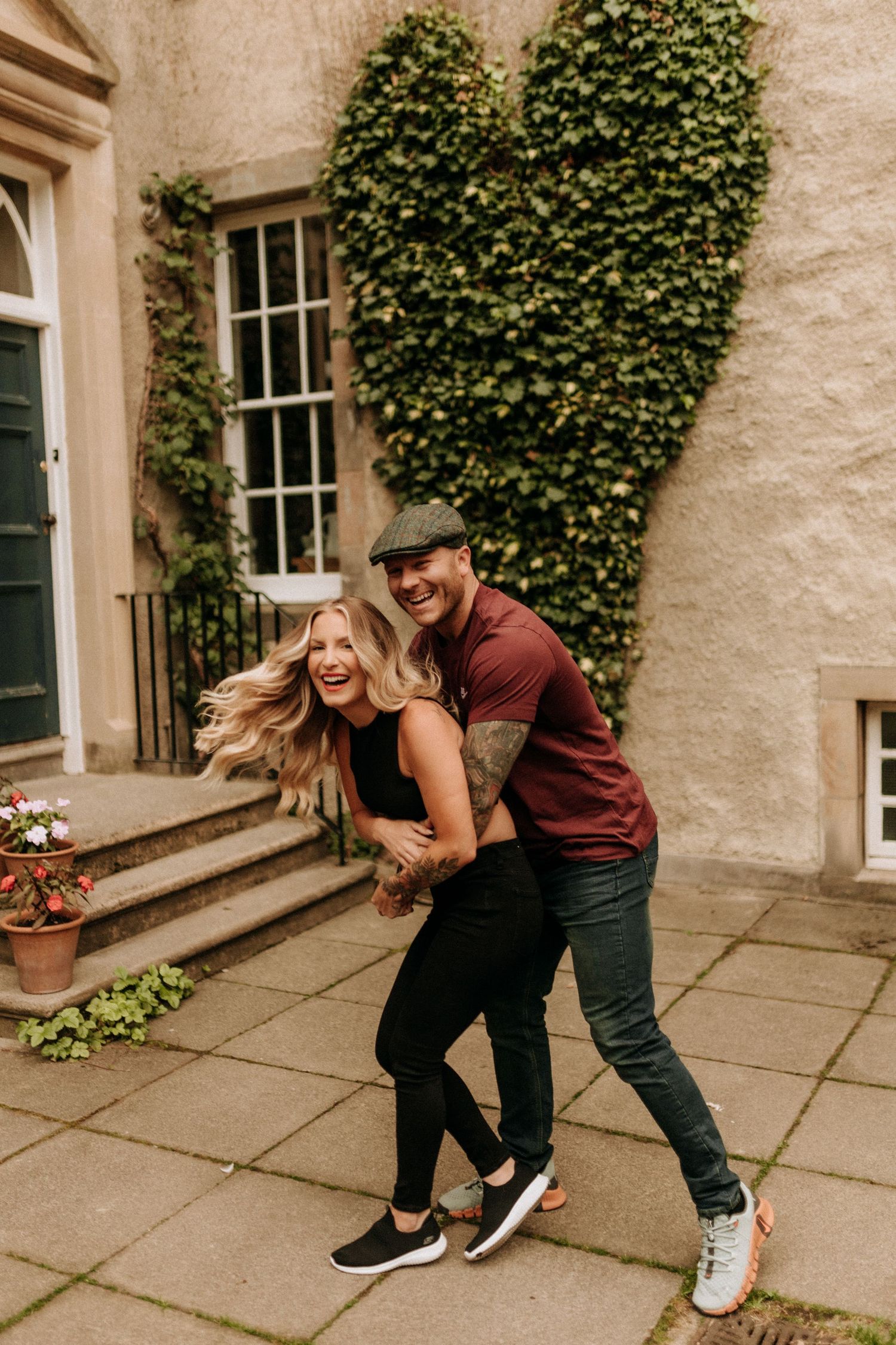 Playful sequence of a couple dancing and dipping near an ivy-covered stone building.