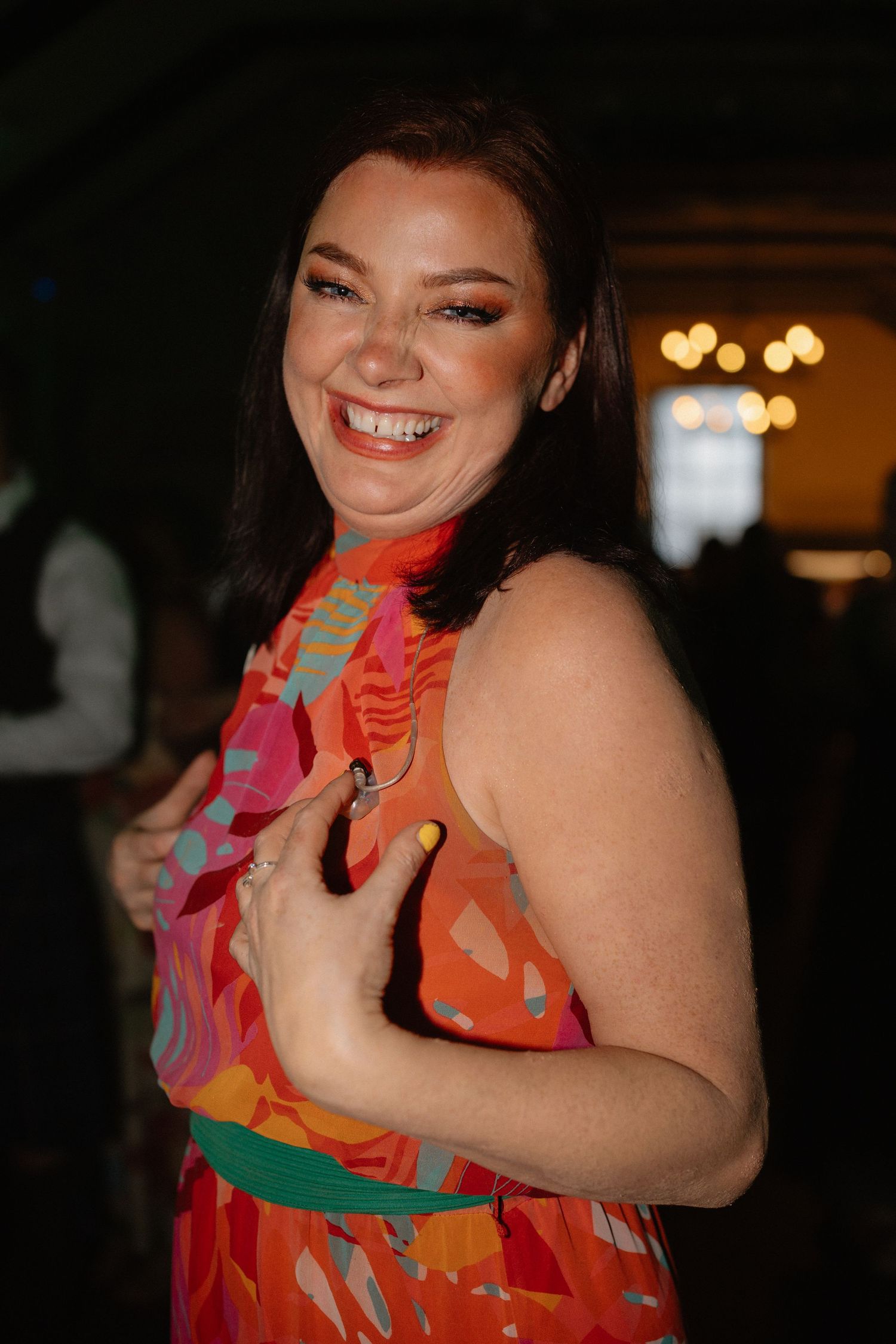 Person in a vibrant floral dress dancing joyfully at an evening celebration.