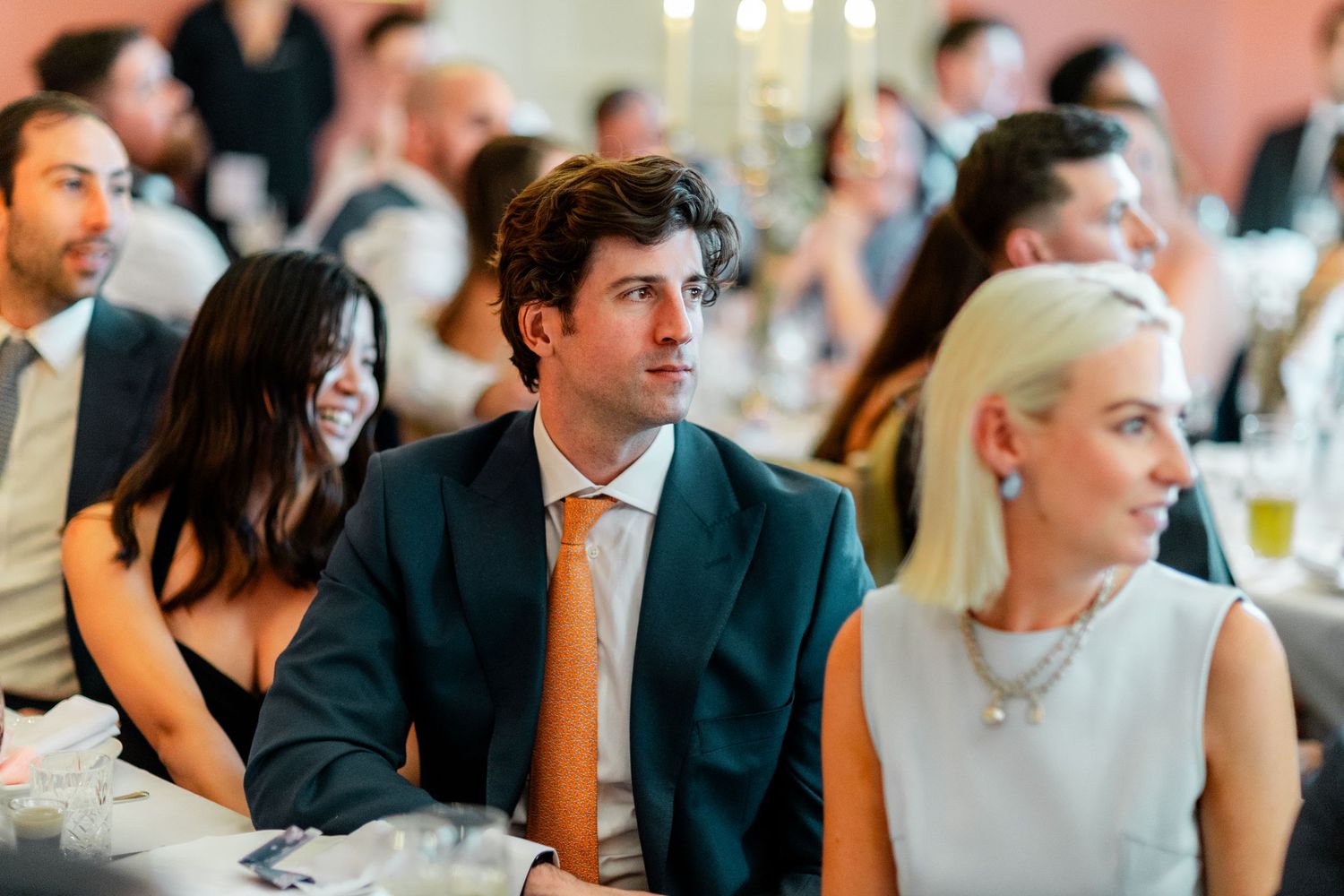 Formal wedding guests enjoying dinner conversation at an elegant indoor reception.