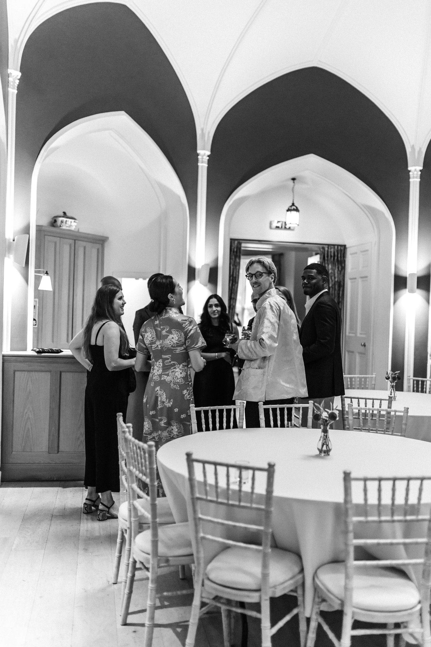 Elegant reception space with arched doorways and white chiavari chairs set for an event.