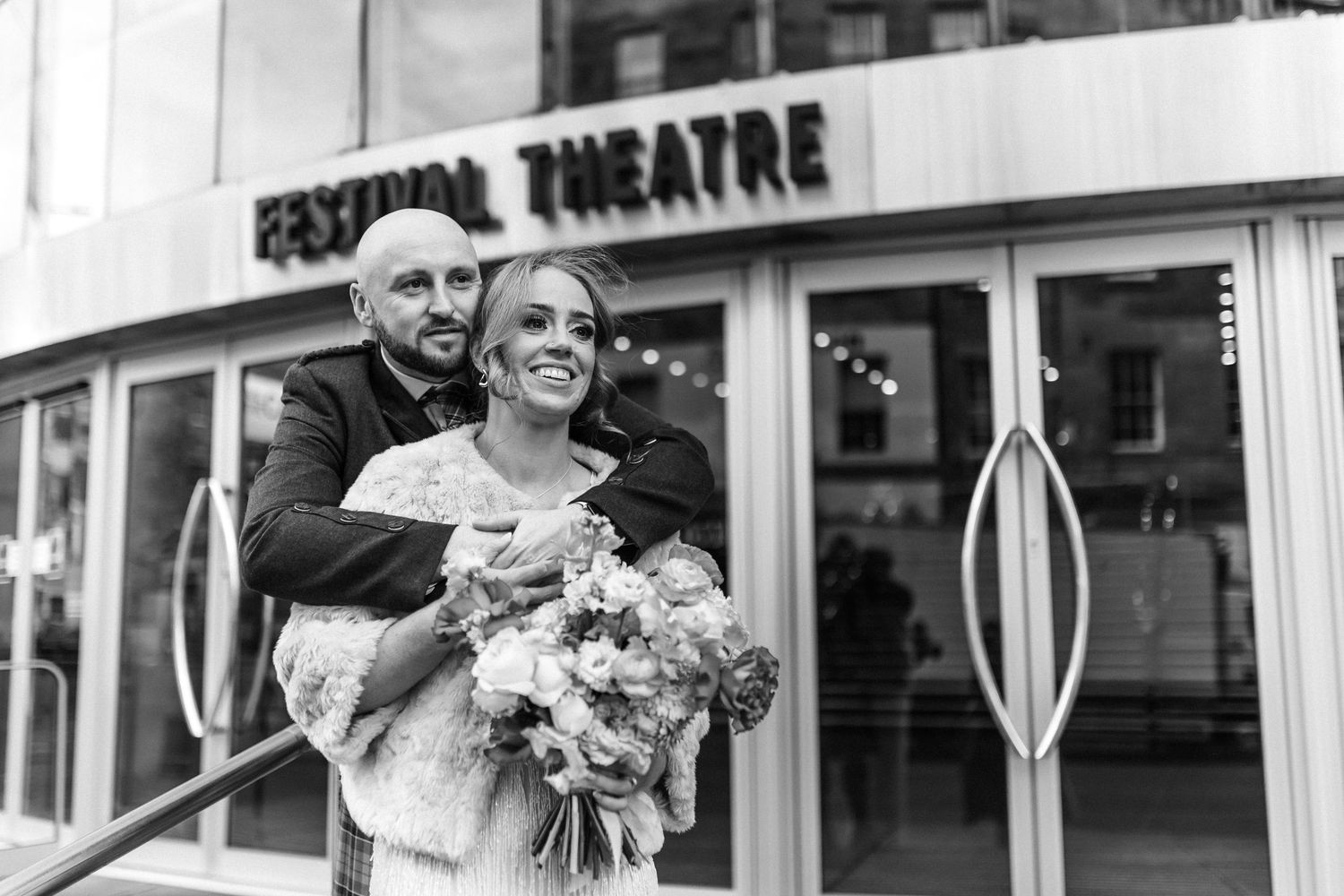 A couple poses outside the Festival Theatre in Edinburgh during their wedding celebration.