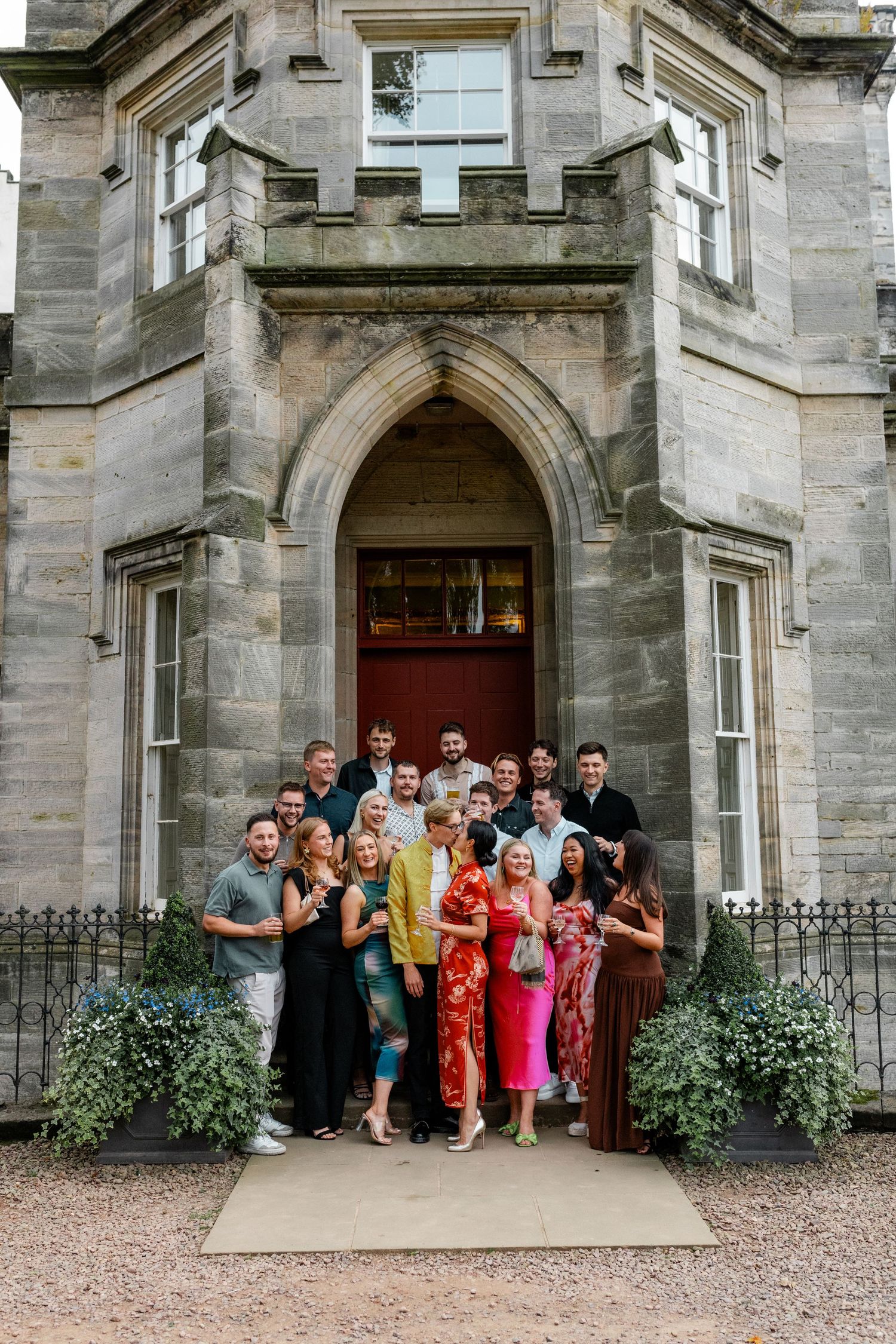 Wedding guests gather for group photos outside a grand stone church entrance.