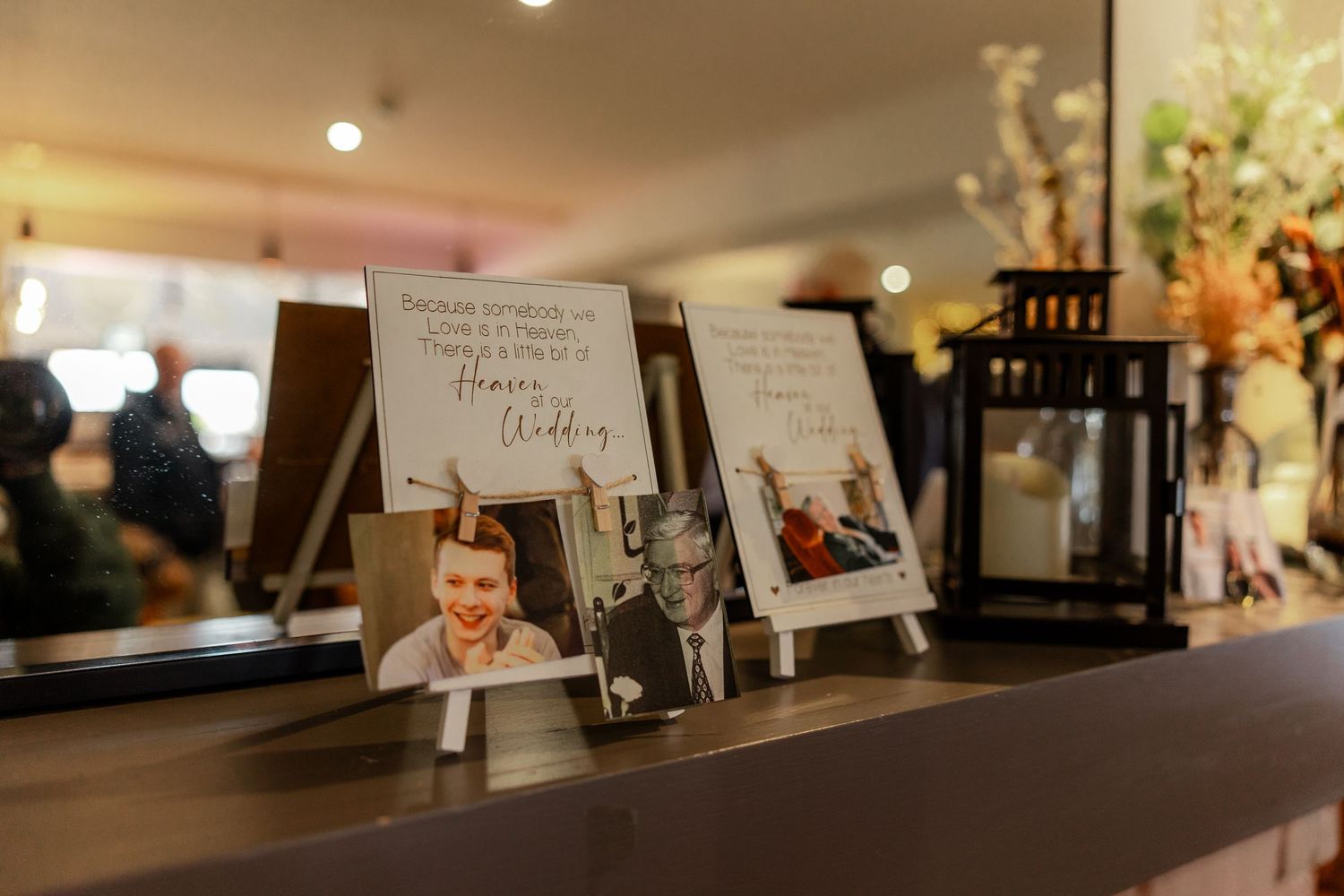 Wedding reception details with framed photos and decorative elements on a dark wooden surface.