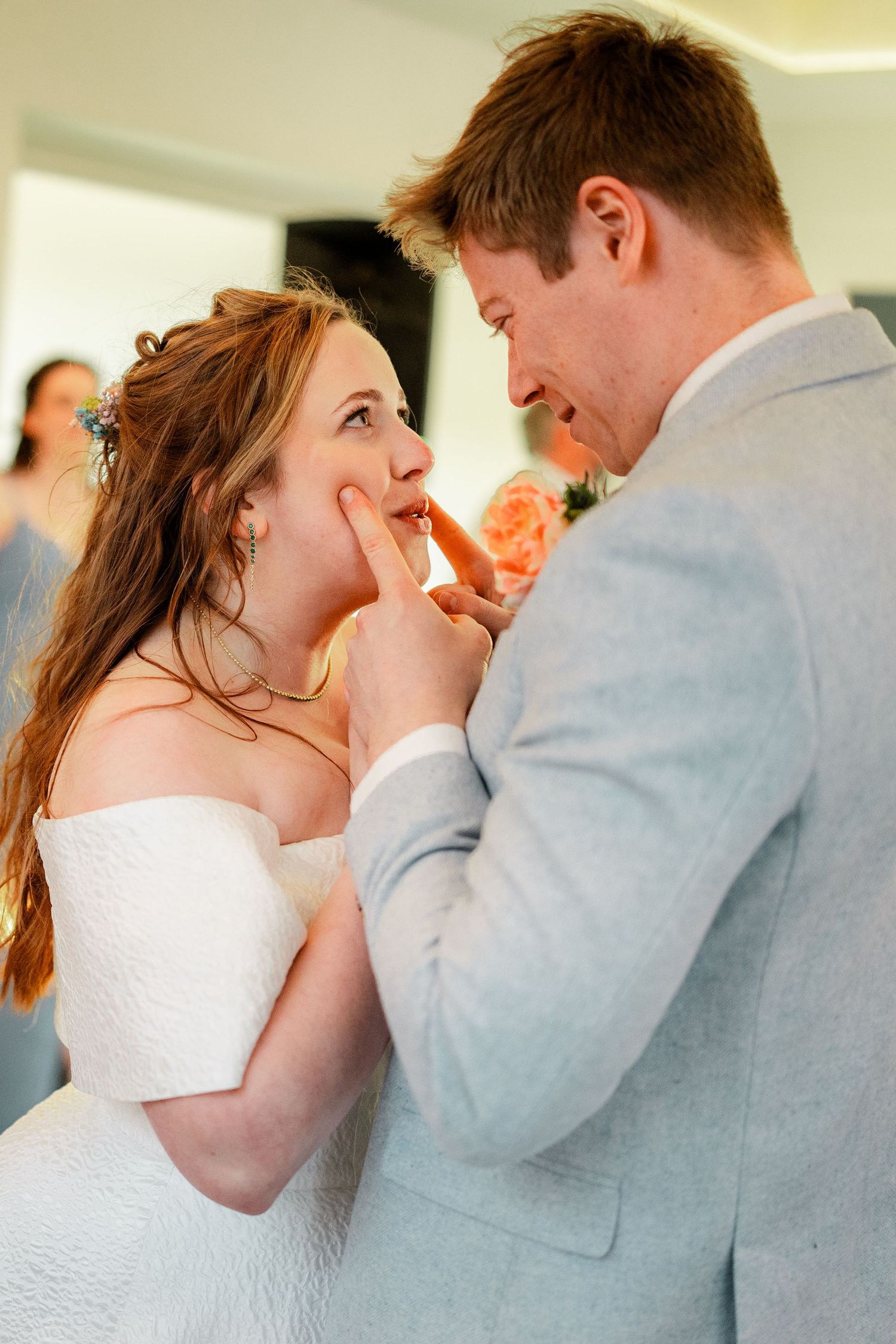 Groom tenderly touches bride's cheek as they share an intimate moment during their wedding reception.