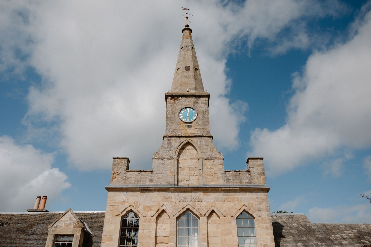 Historic church buildings with Gothic architecture and clock towers stand against a blue sky with white clouds.
