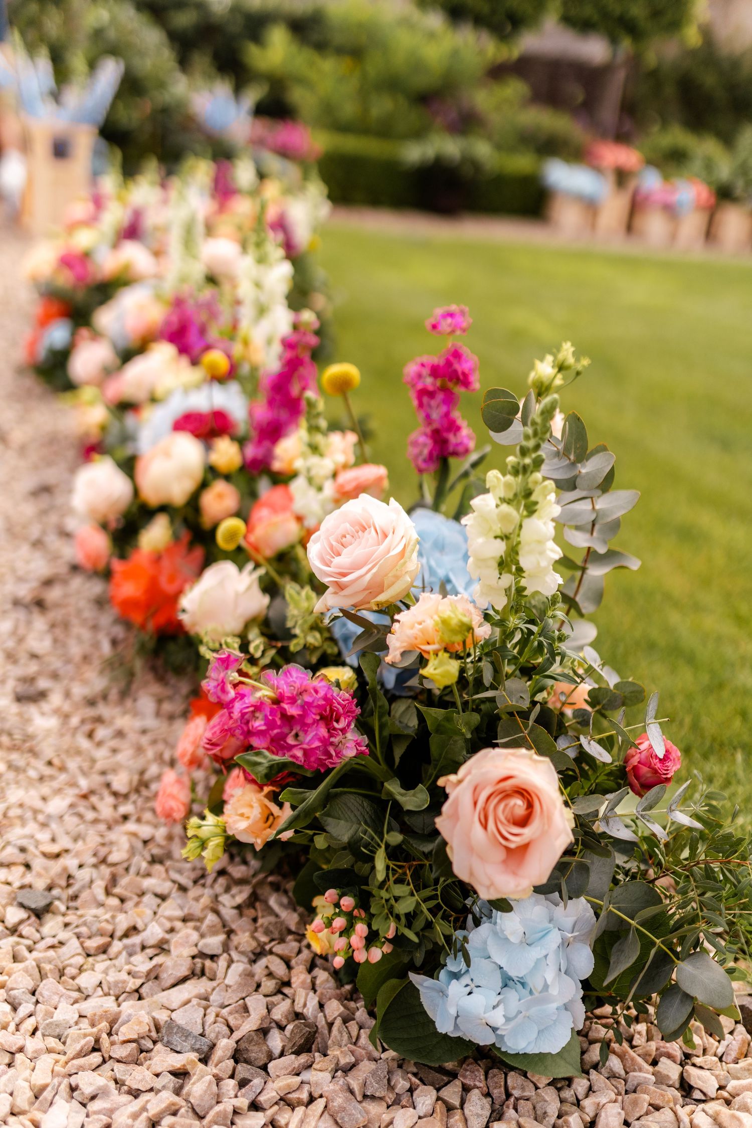 Colorful floral arrangements with roses and hydrangeas decorating stone pathway.