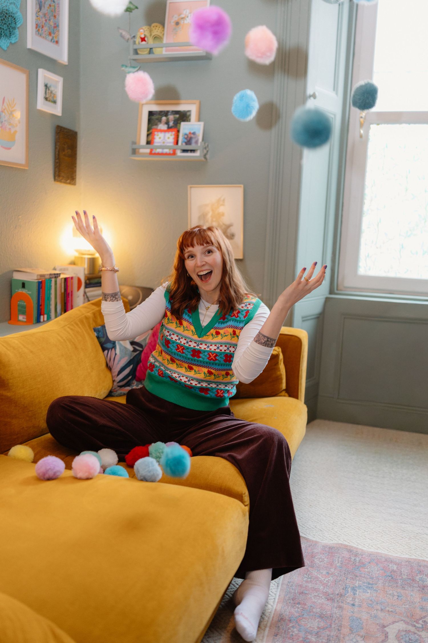 Playful scene on a yellow couch with colorful pom poms and festive decorations.