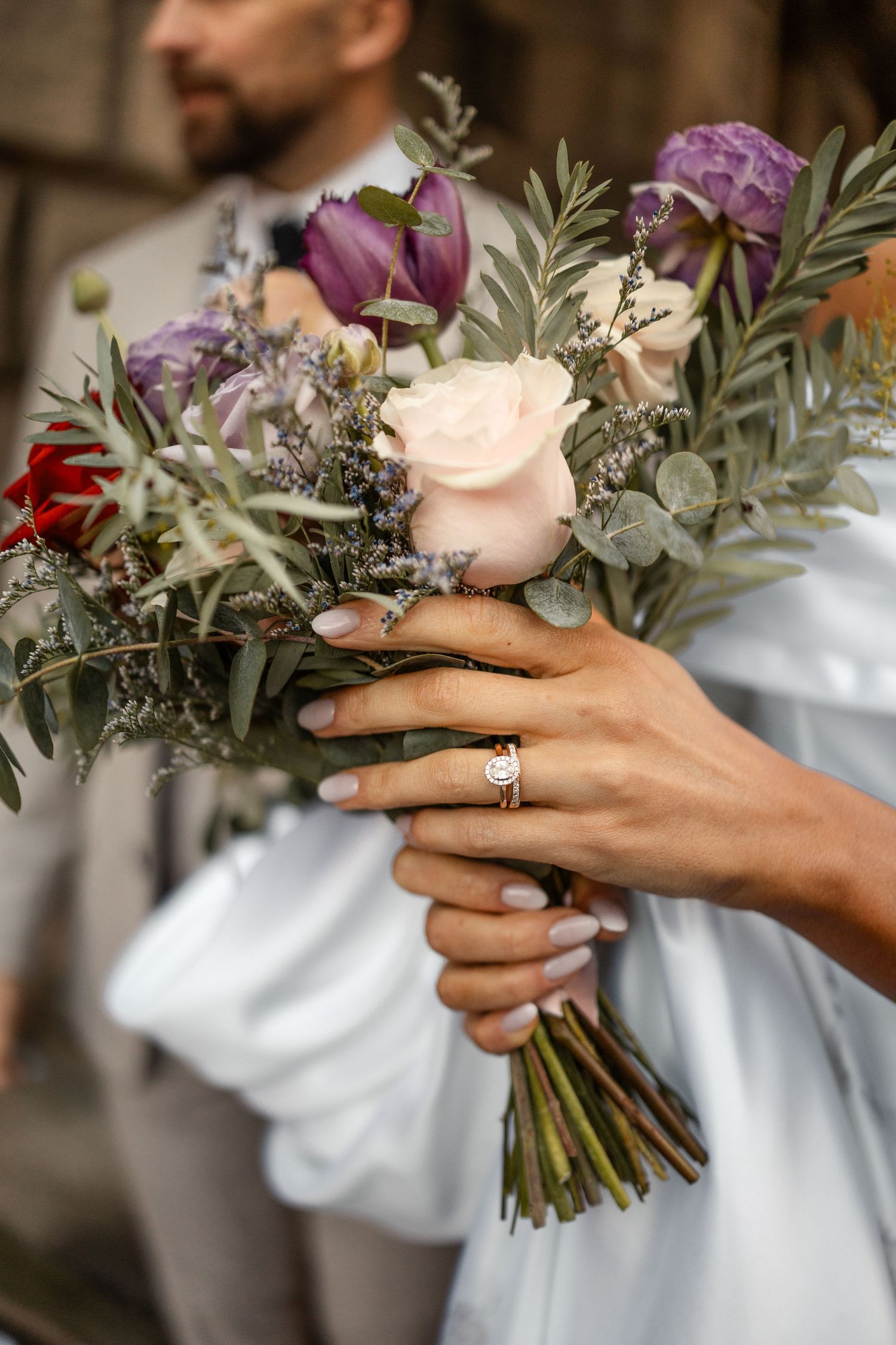 Close-up shots of hands holding a beautiful wedding bouquet with purple flowers and eucalyptus.